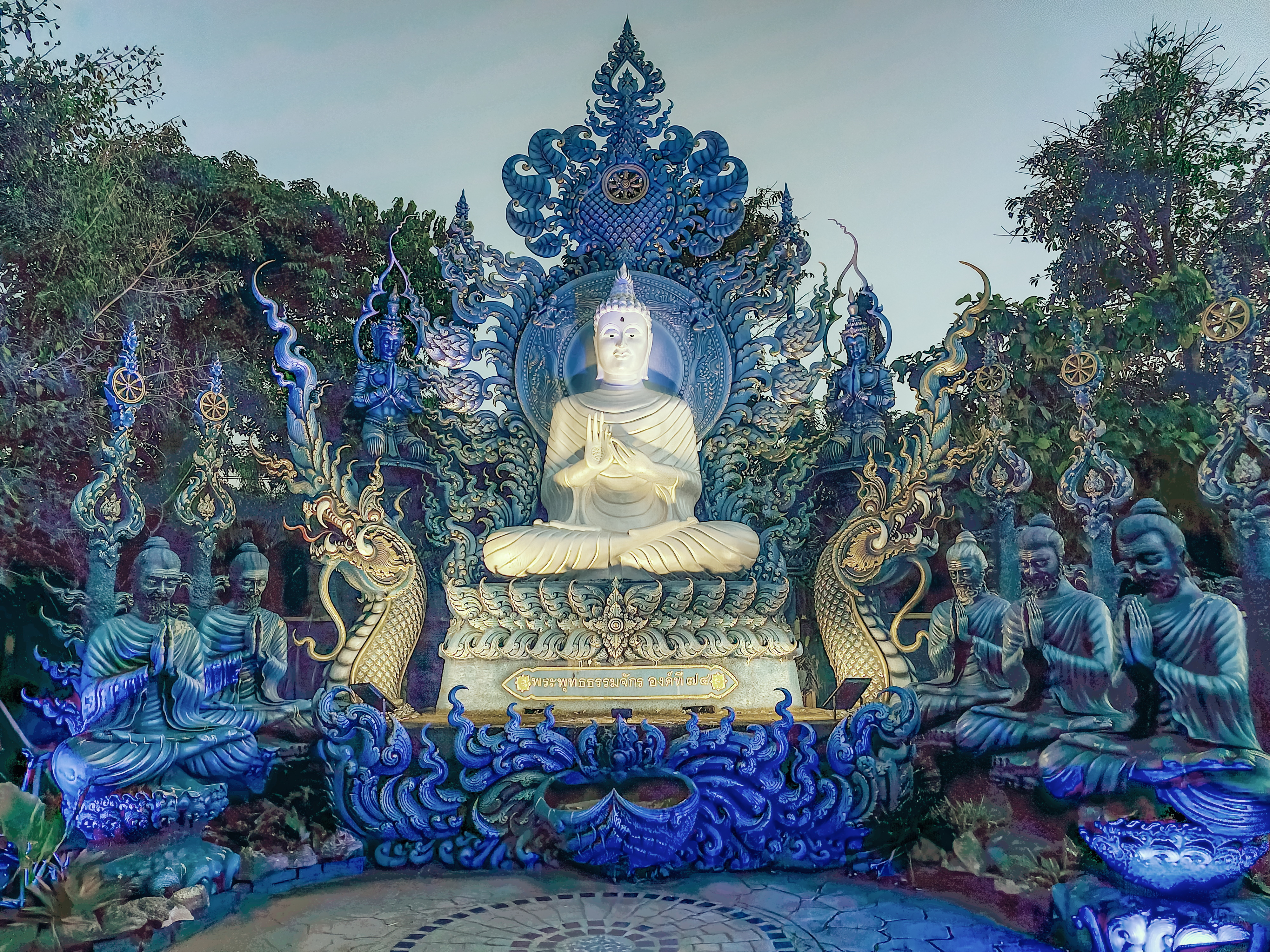 Praying monks and Buddha statues at Wat Rong Suea Ten Blue temple, Chiang Rai, Thailand