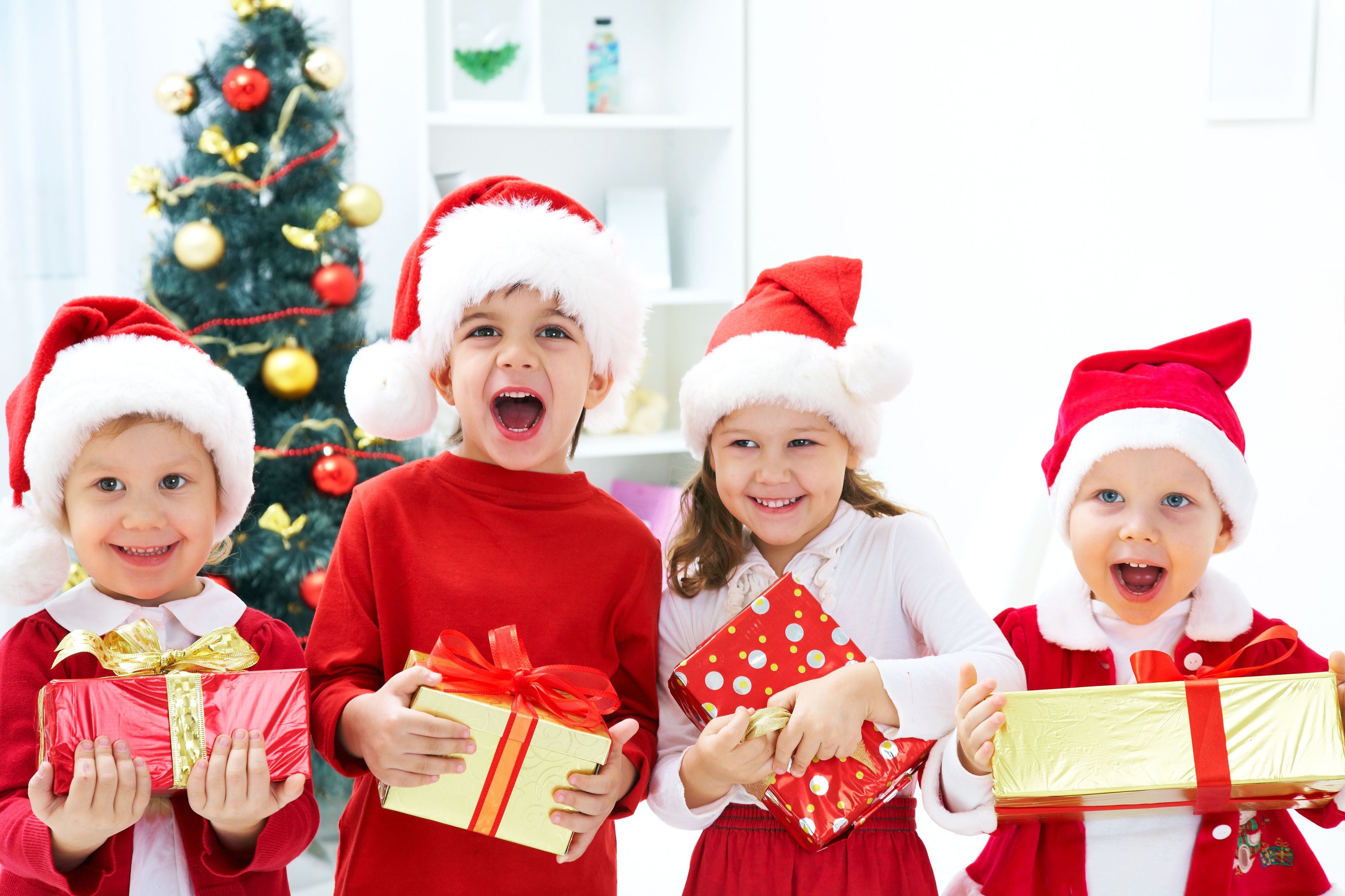 Kids in Christmas outfits posing happily with their gifts