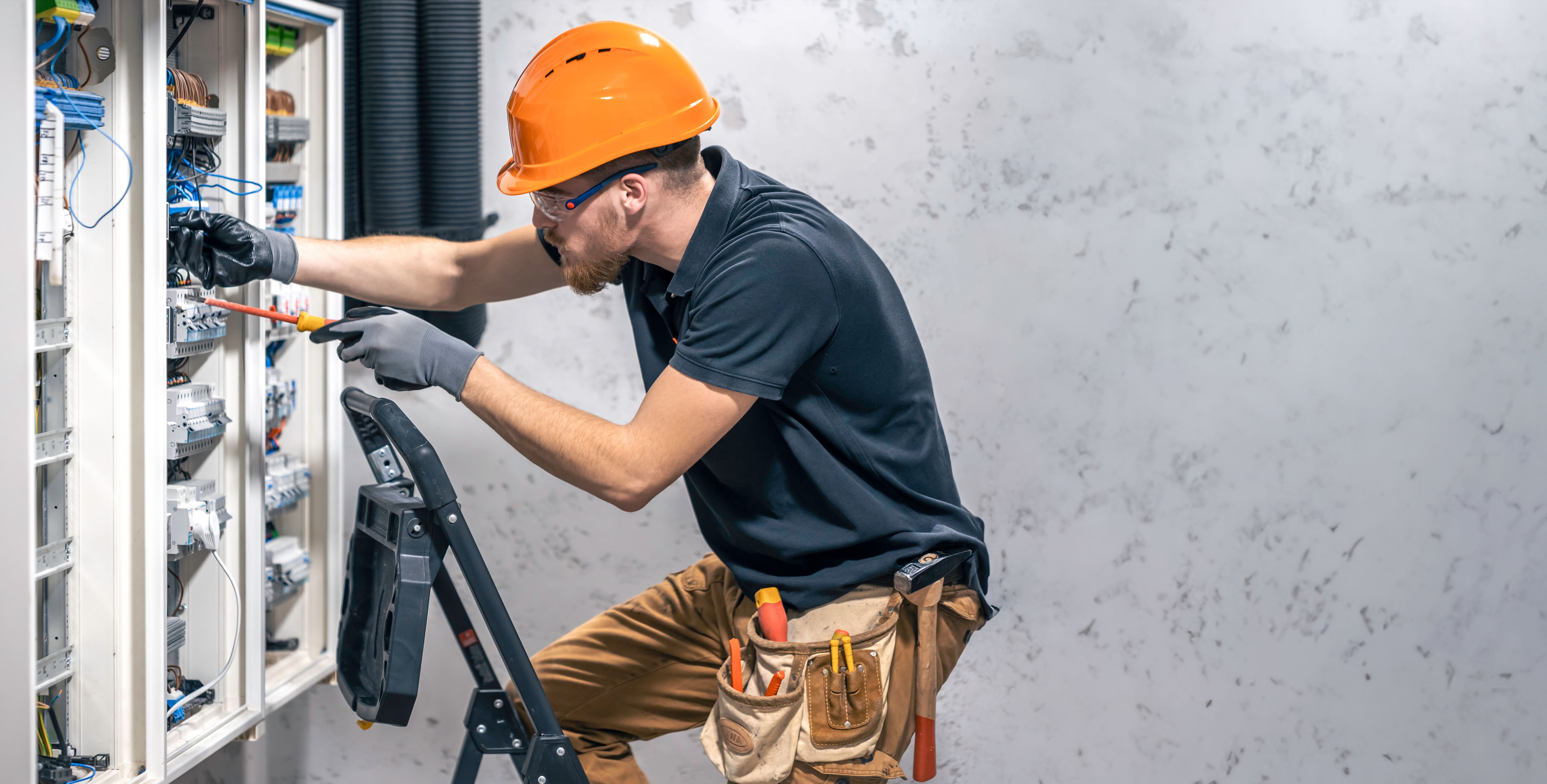 Electrician working in switchboard with electrical connection cable, copy space.