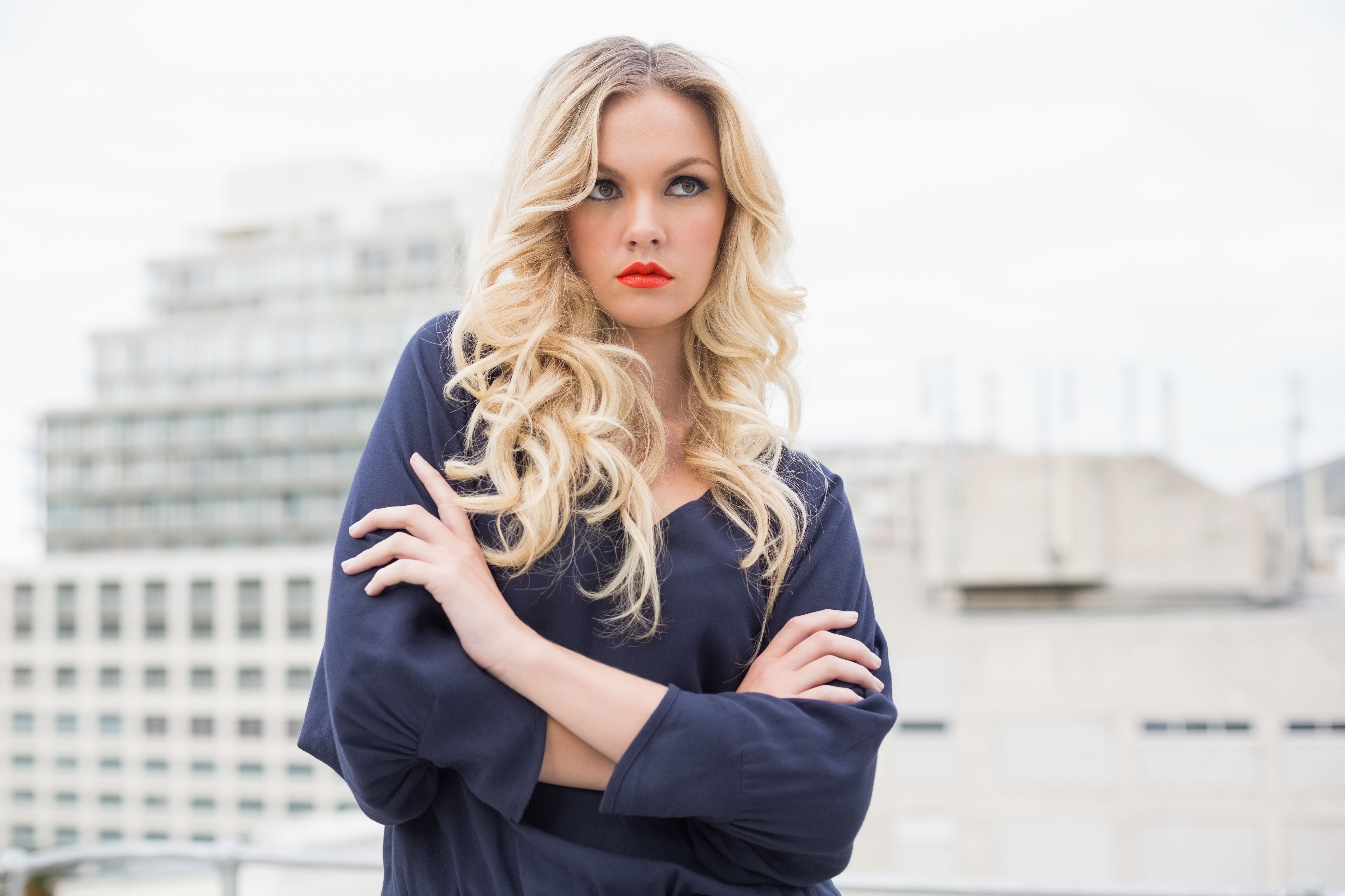 Thoughtful gorgeous blonde with red lips posing outdoors