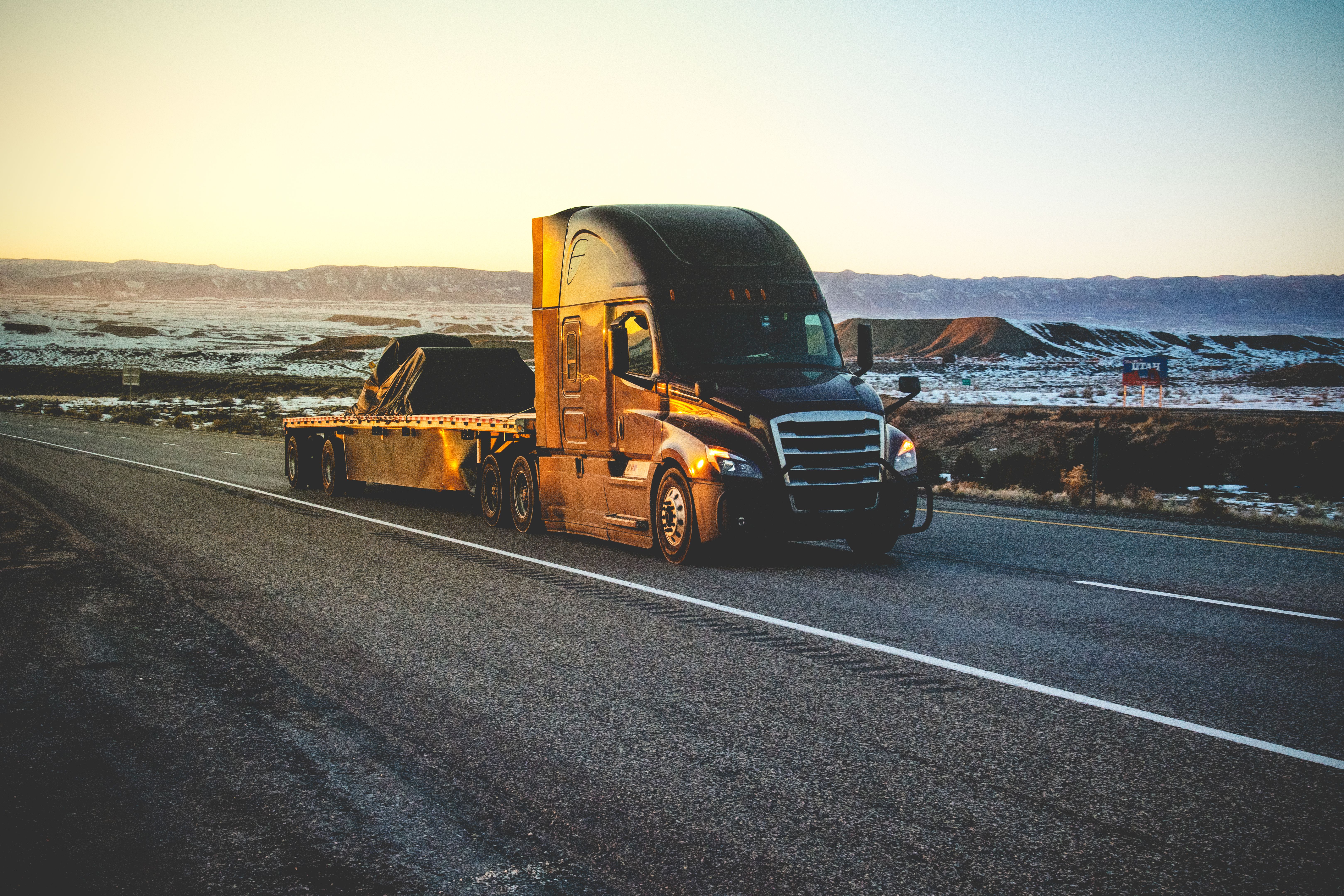 Long Haul Semi Truck Speeding Down Highway In A Snowy Desert Landscape