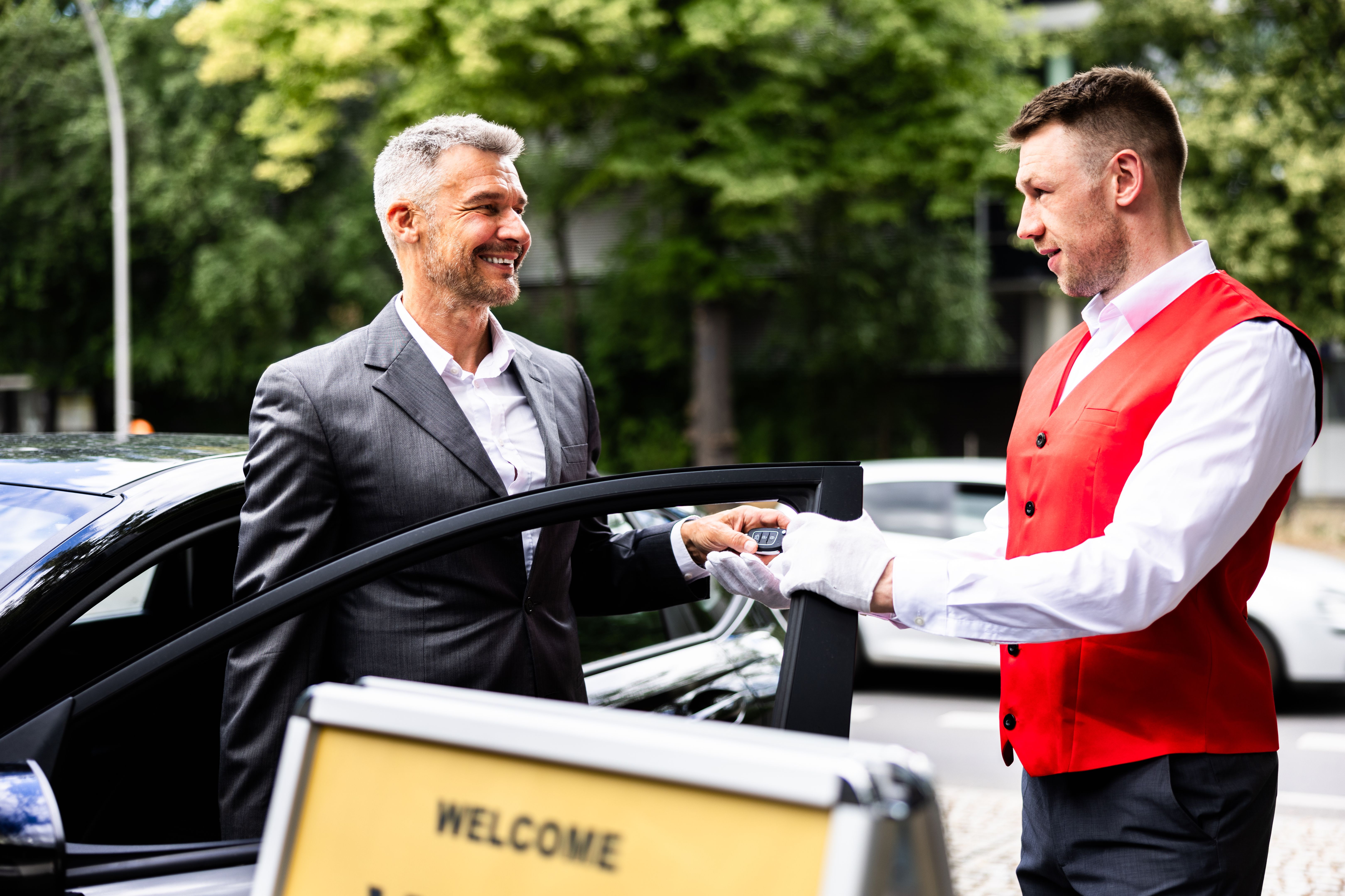 Luxury Car Rental Service: Professional Businessman Smiling as Valet Hands Over Luxury Car Rental Service: Professional Businessman Smiling as Valet Hands Over