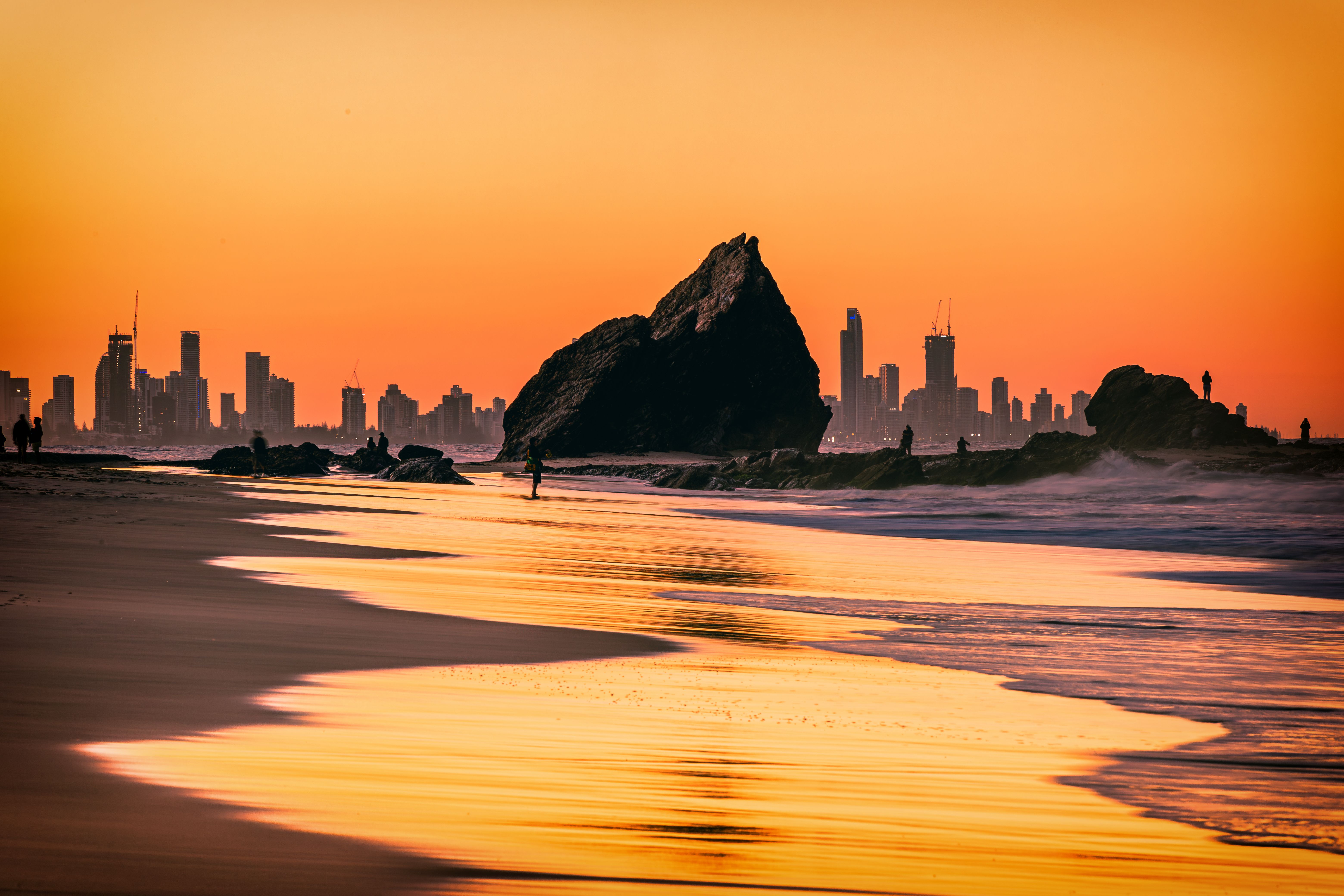 The sunset view of the Currumbin Beach in the twilight and the urban skyline of  Gold Coast in the distance