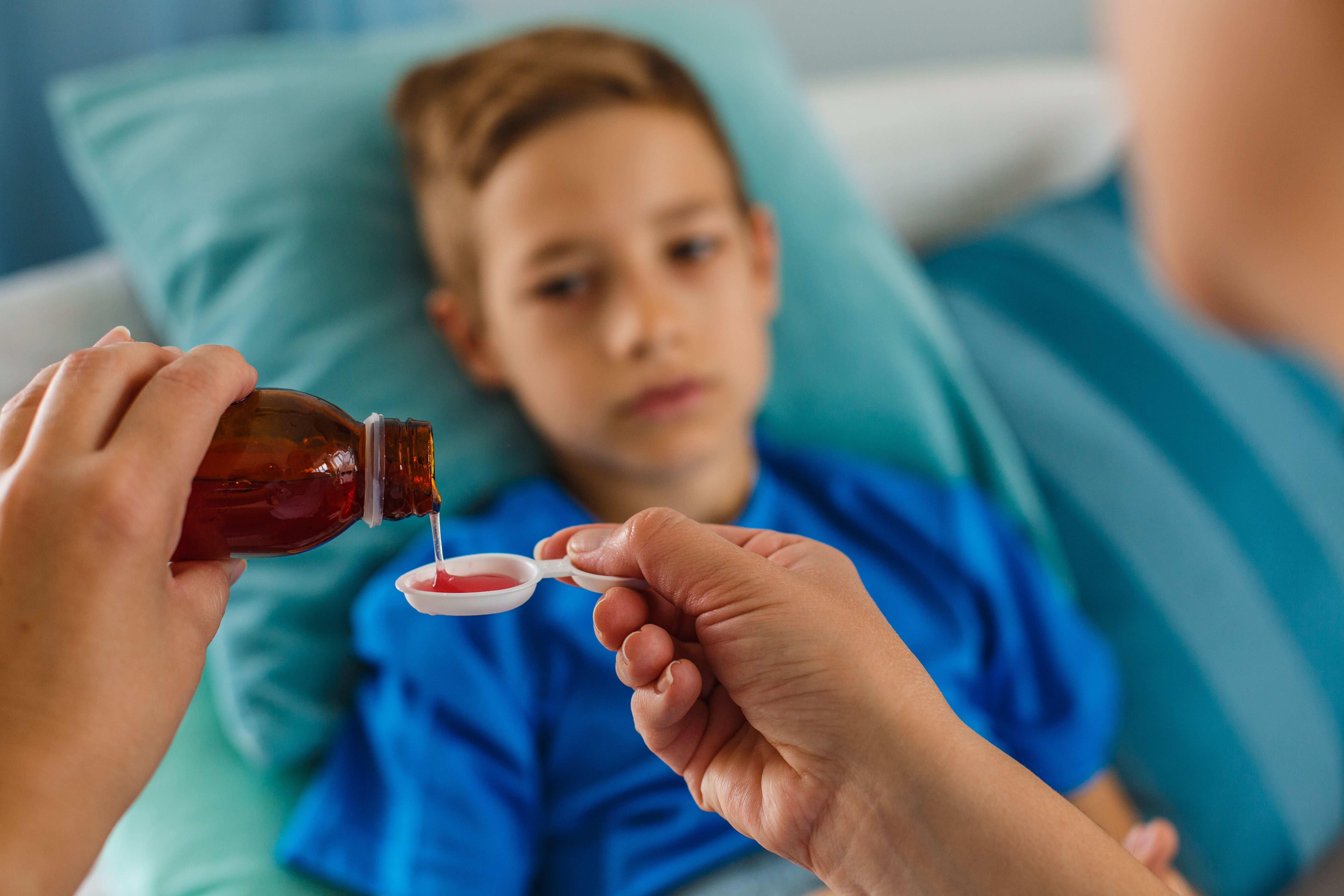 Woman pouring syrup for sick boy