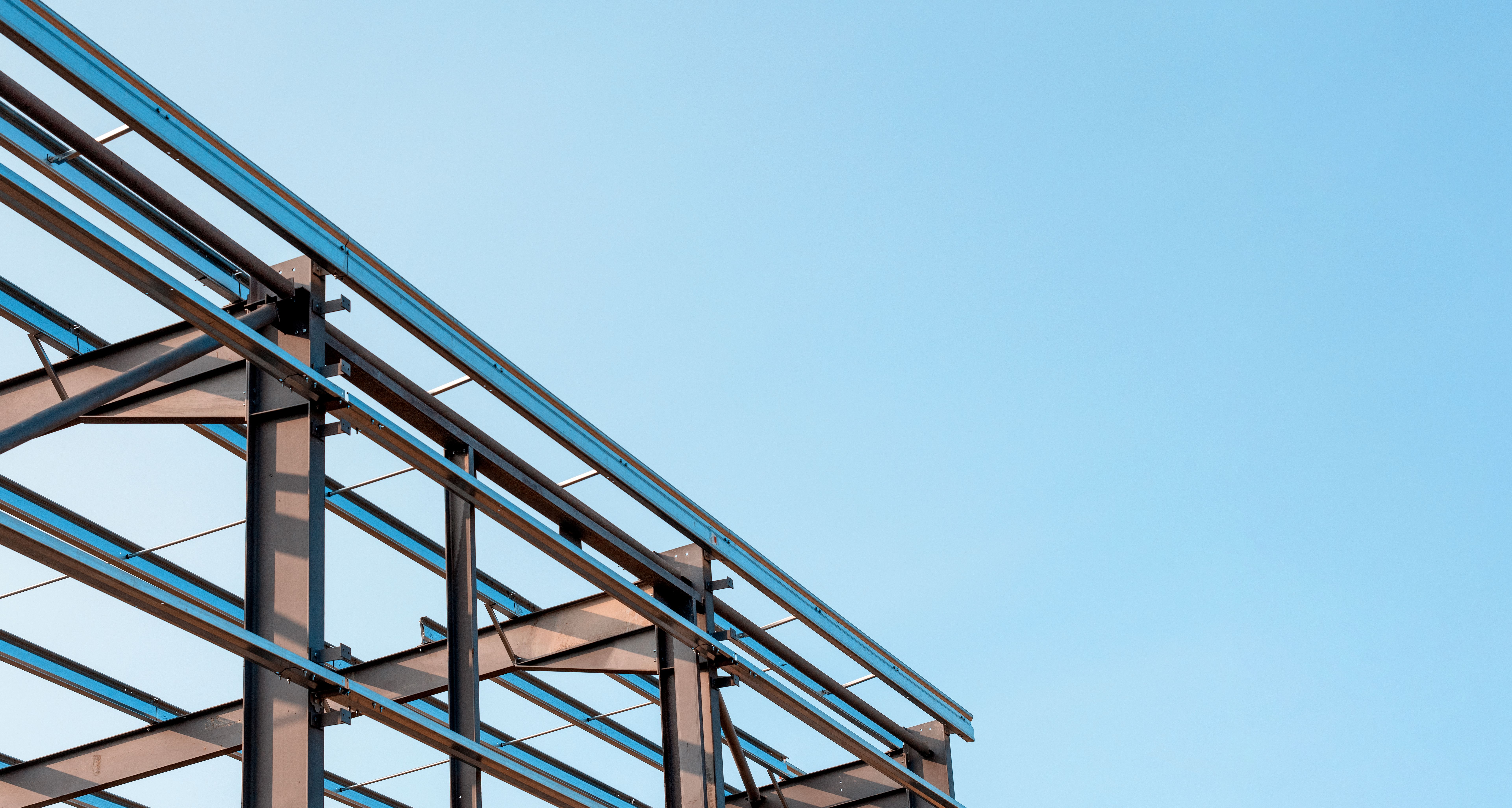 Steel framework of a building under construction against a clear blue sky in bright daylight