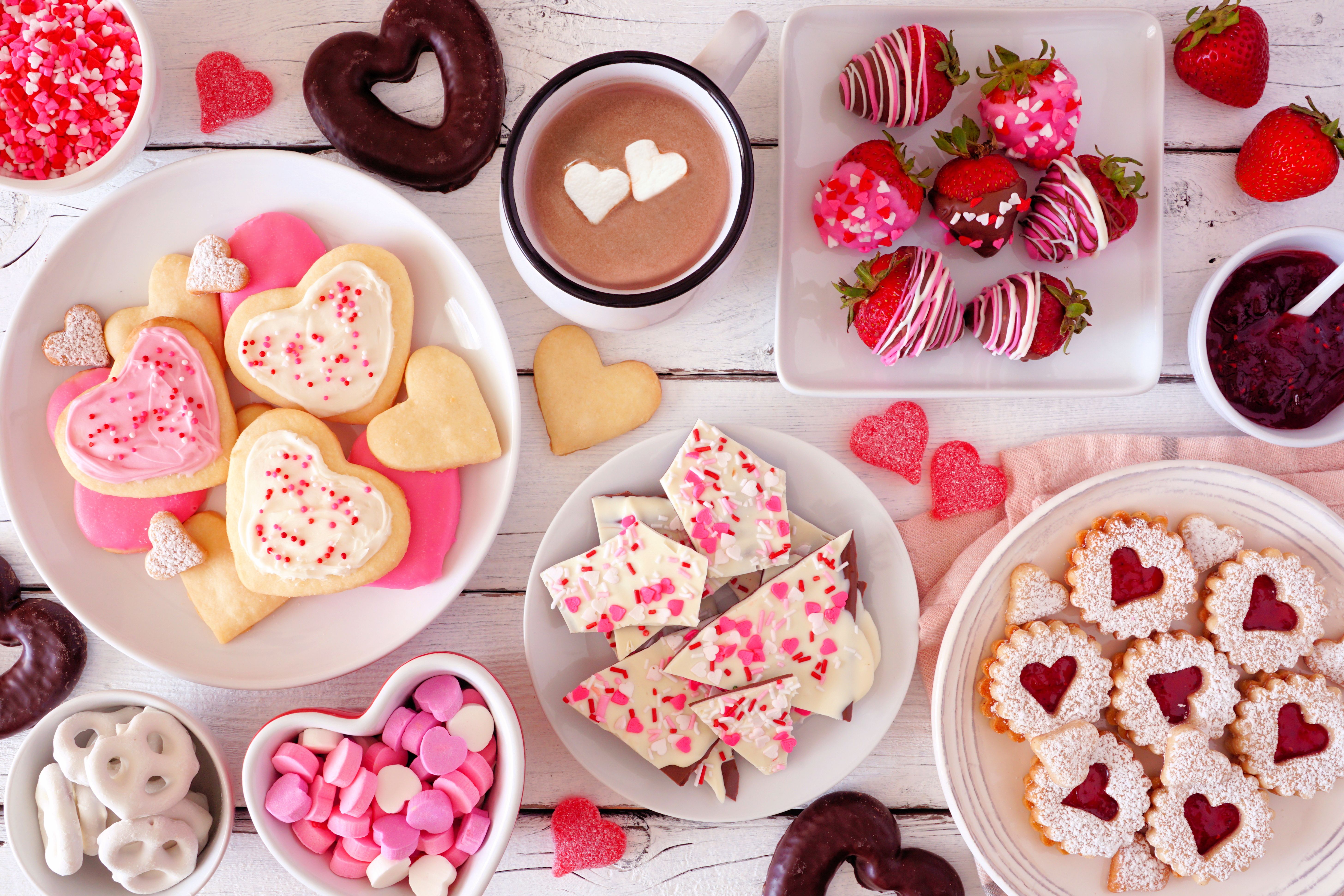 Valentines Day table scene with a selection of sweets and cookies, top view over a white wood background