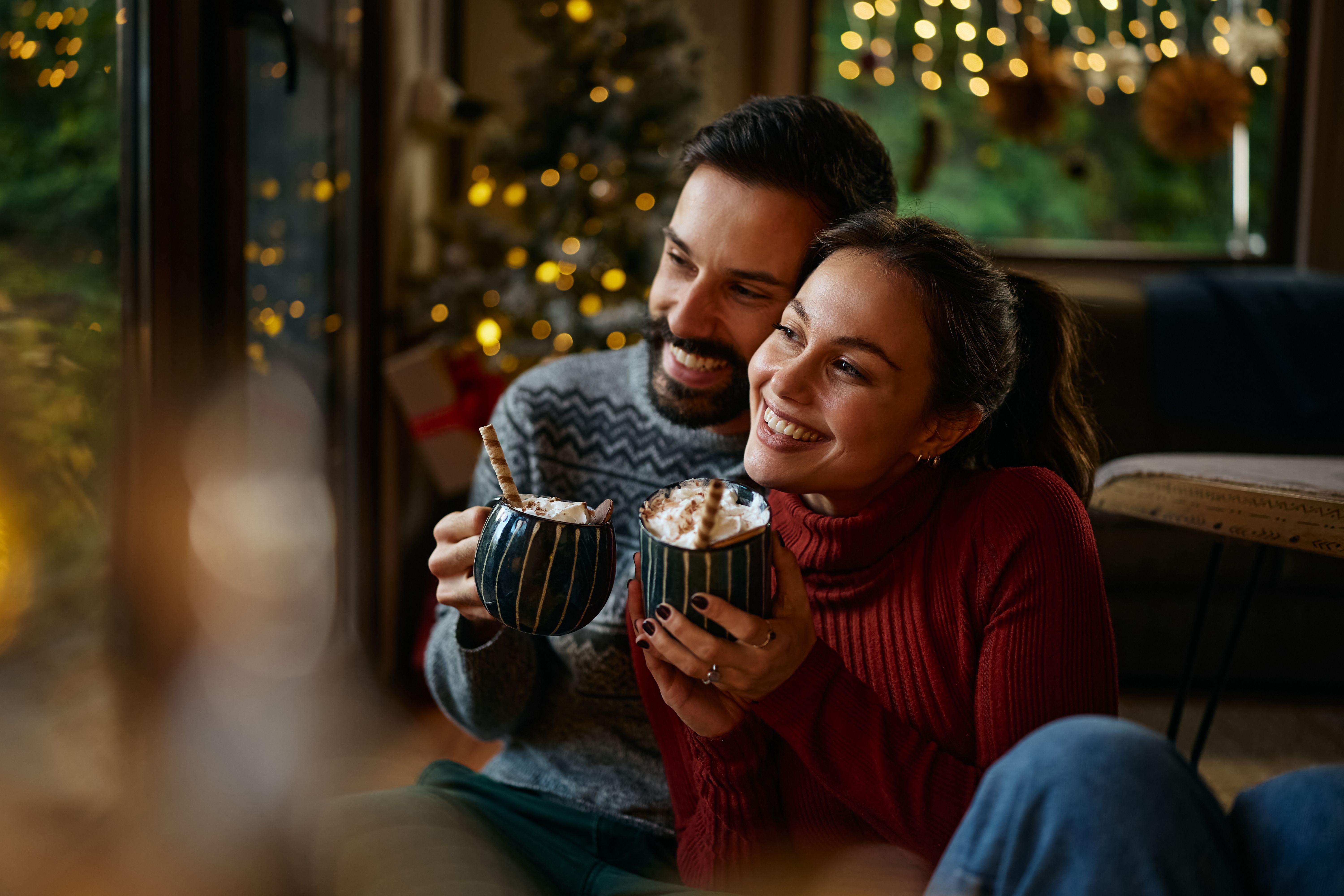 Happy couple in love enjoying in cup hot cocoa with marshmallows on Christmas.