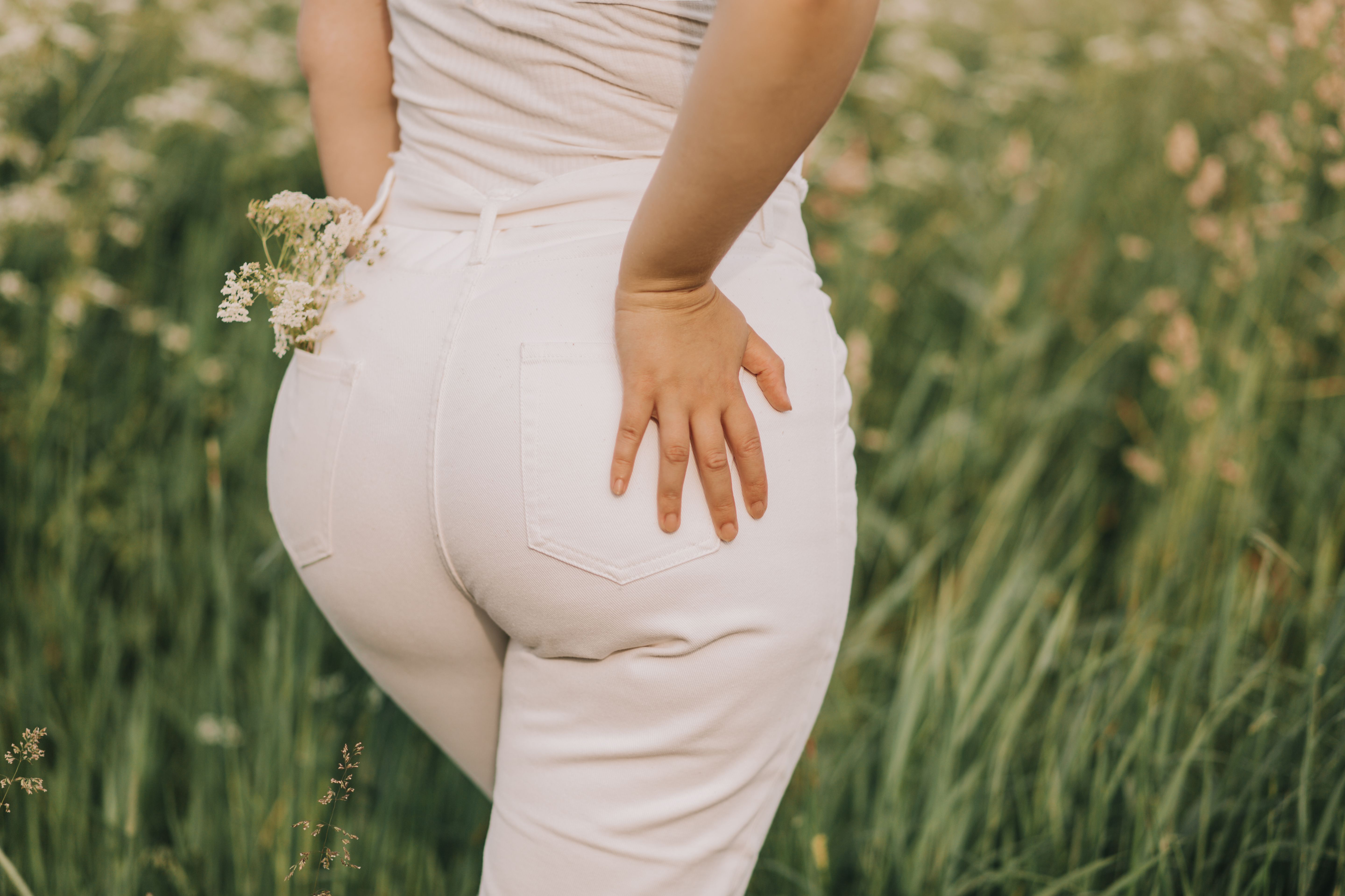 Closeup of a woman in white jeans on a field background.