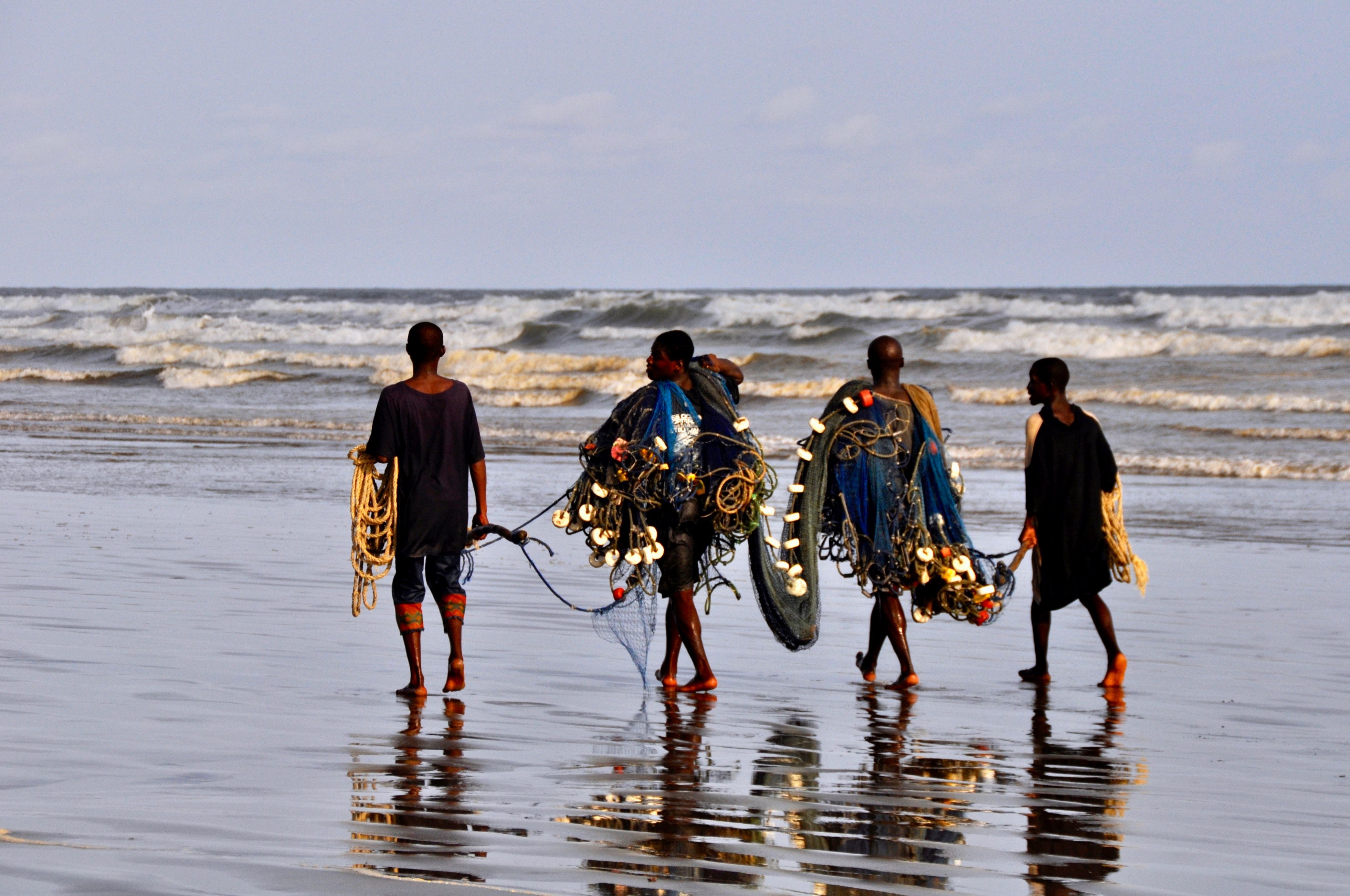 Four Fishermen Are Walking On The Beach