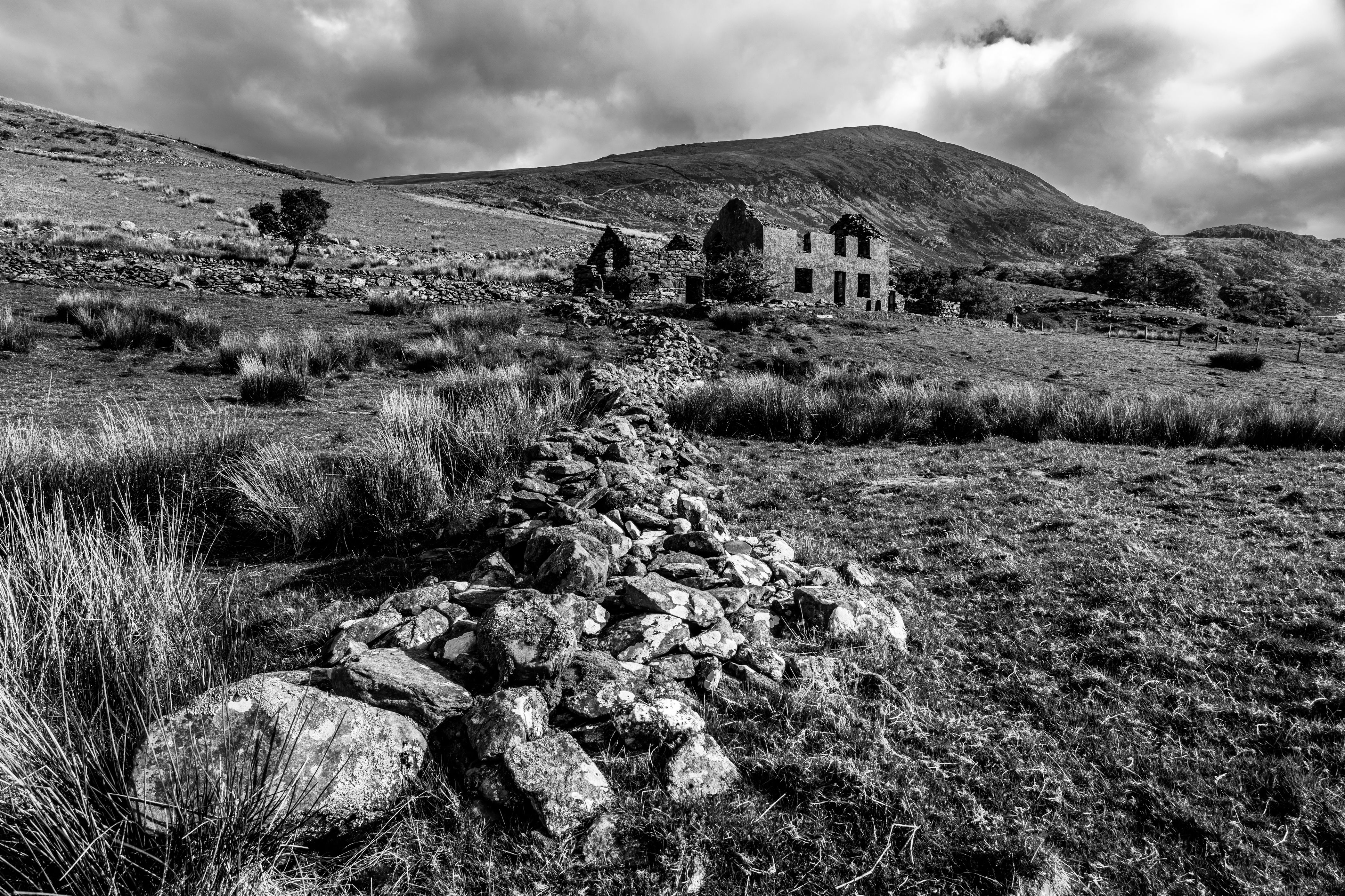 Black and white view of derelict architecture in countryside under moody sky, Cwmstradllyn, Gwynedd, Snowdonia National Park, Wales, Britain