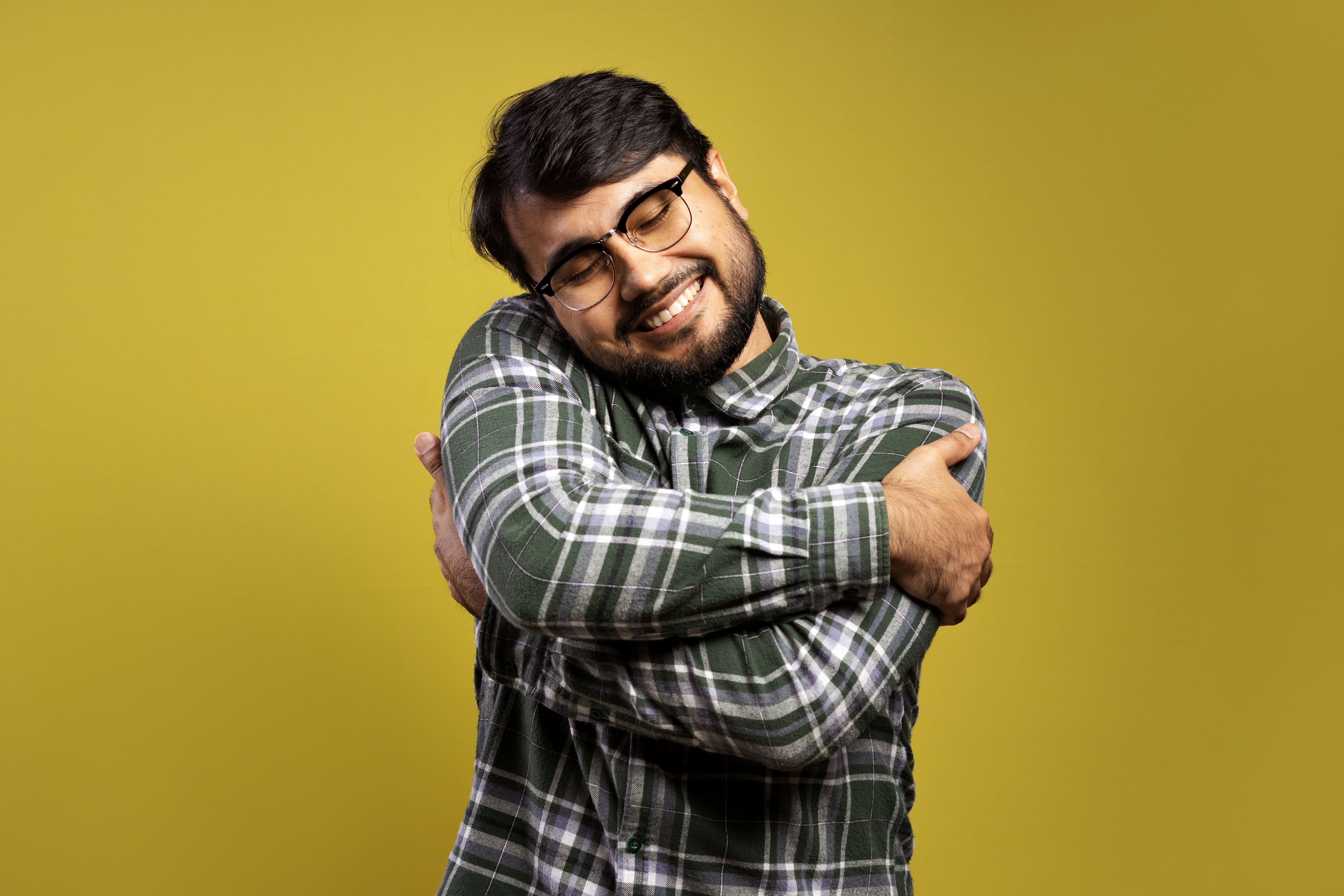 man smiling and giving himself a big hug