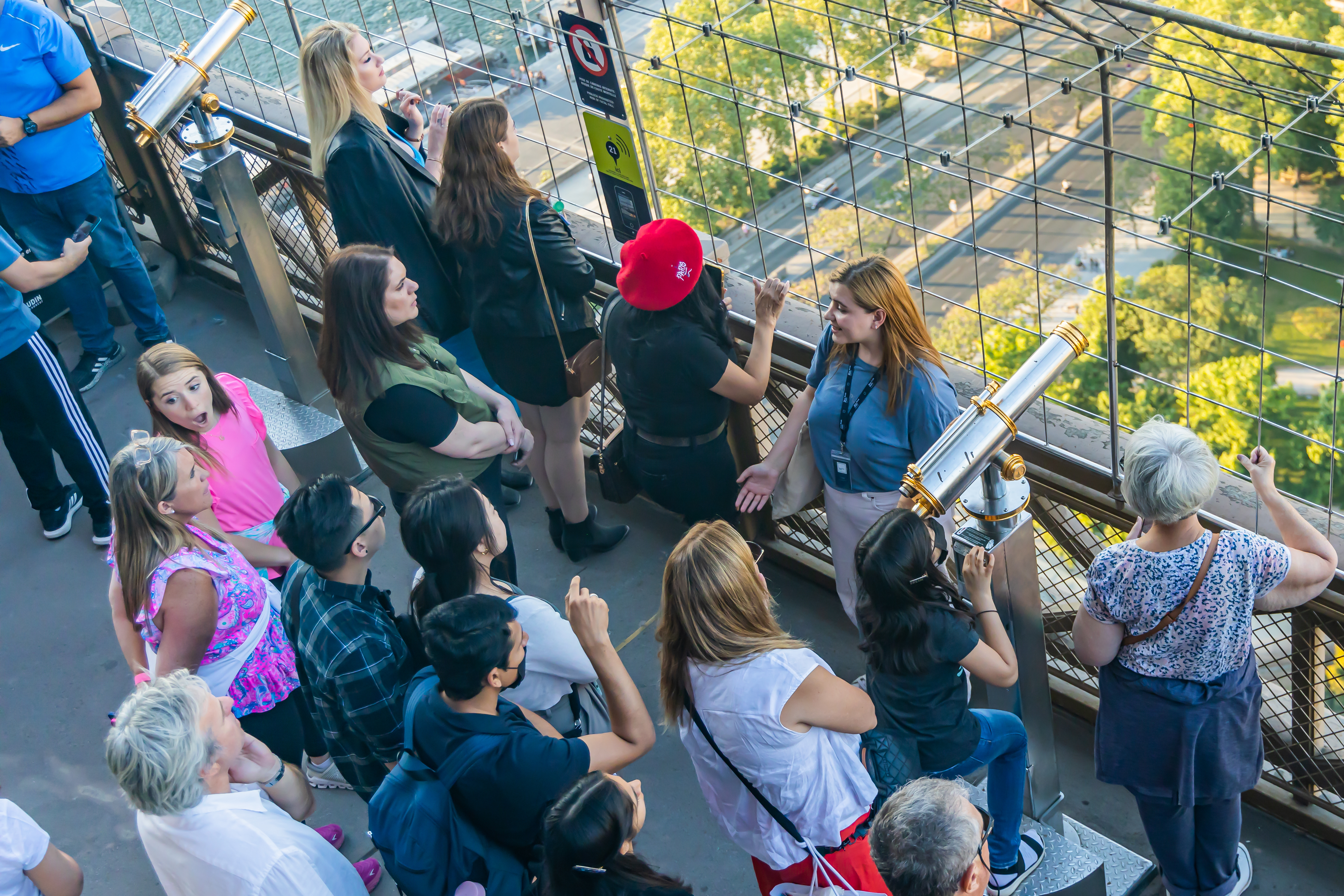 Group of tourists listening to a tour guide while visiting the Eiffel Tower Group of tourists listening to a tour guide while visiting the Eiffel Tower