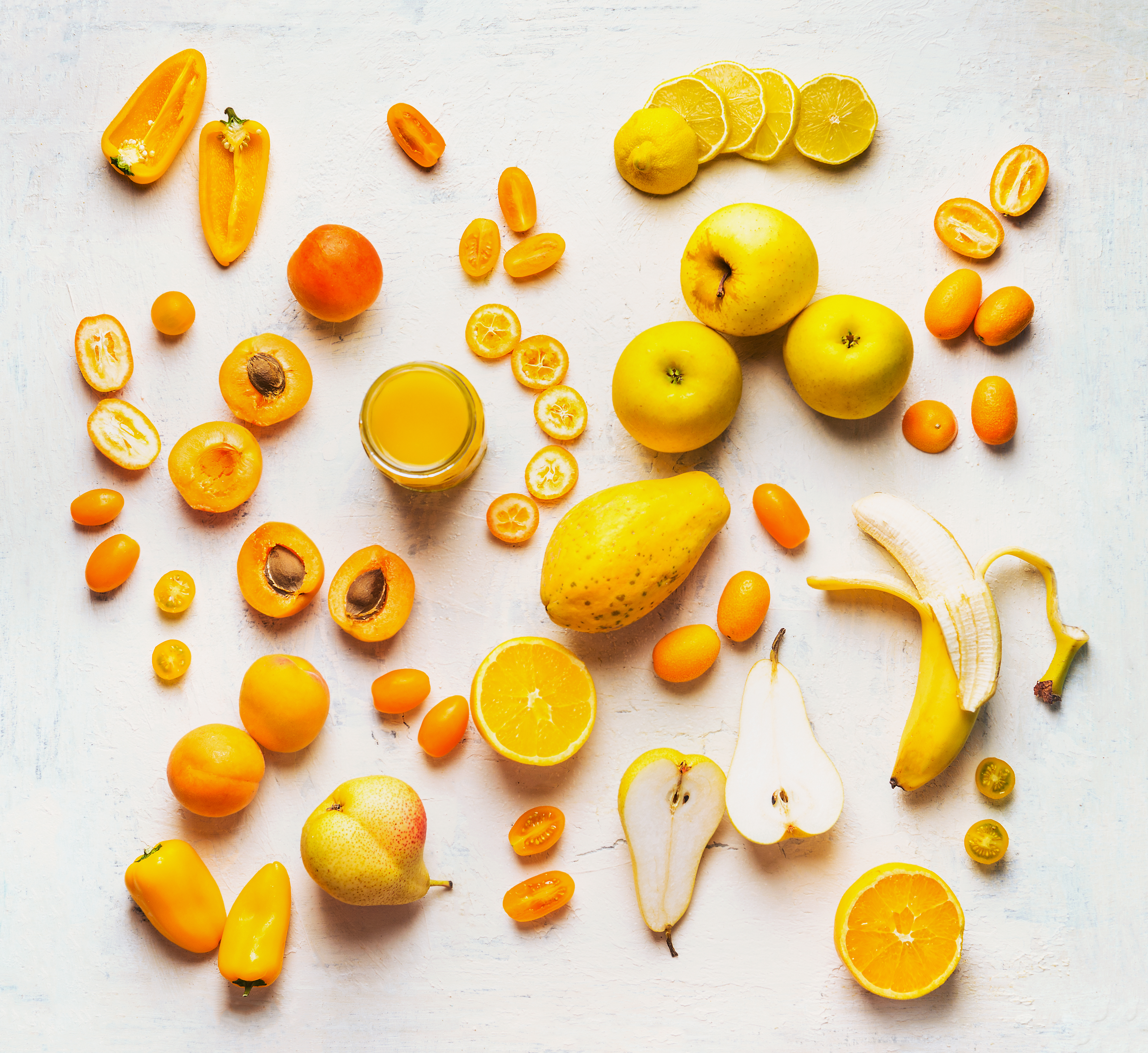 Various yellow and orange color fruits and vegetables on white table background. Flat lay