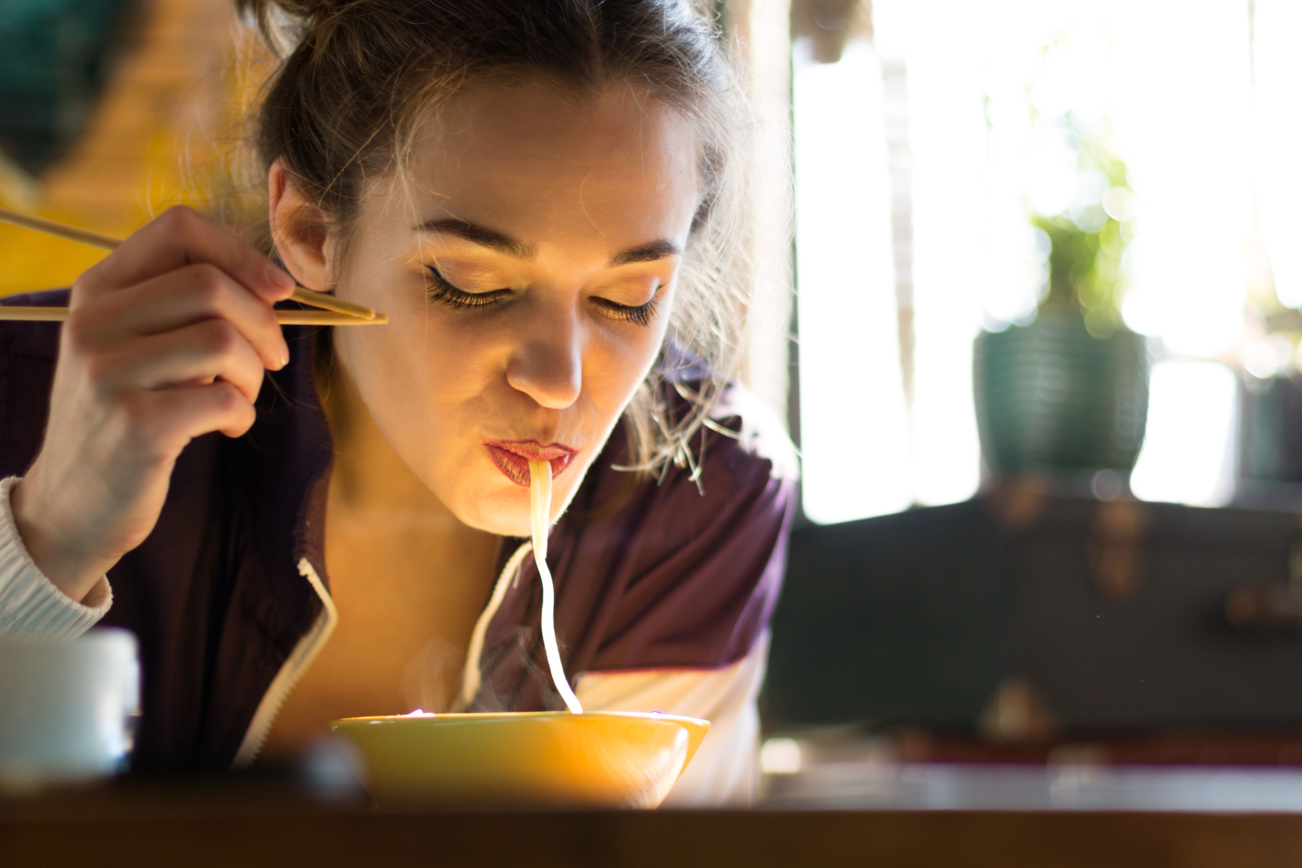Young Woman Eating with Chopsticks