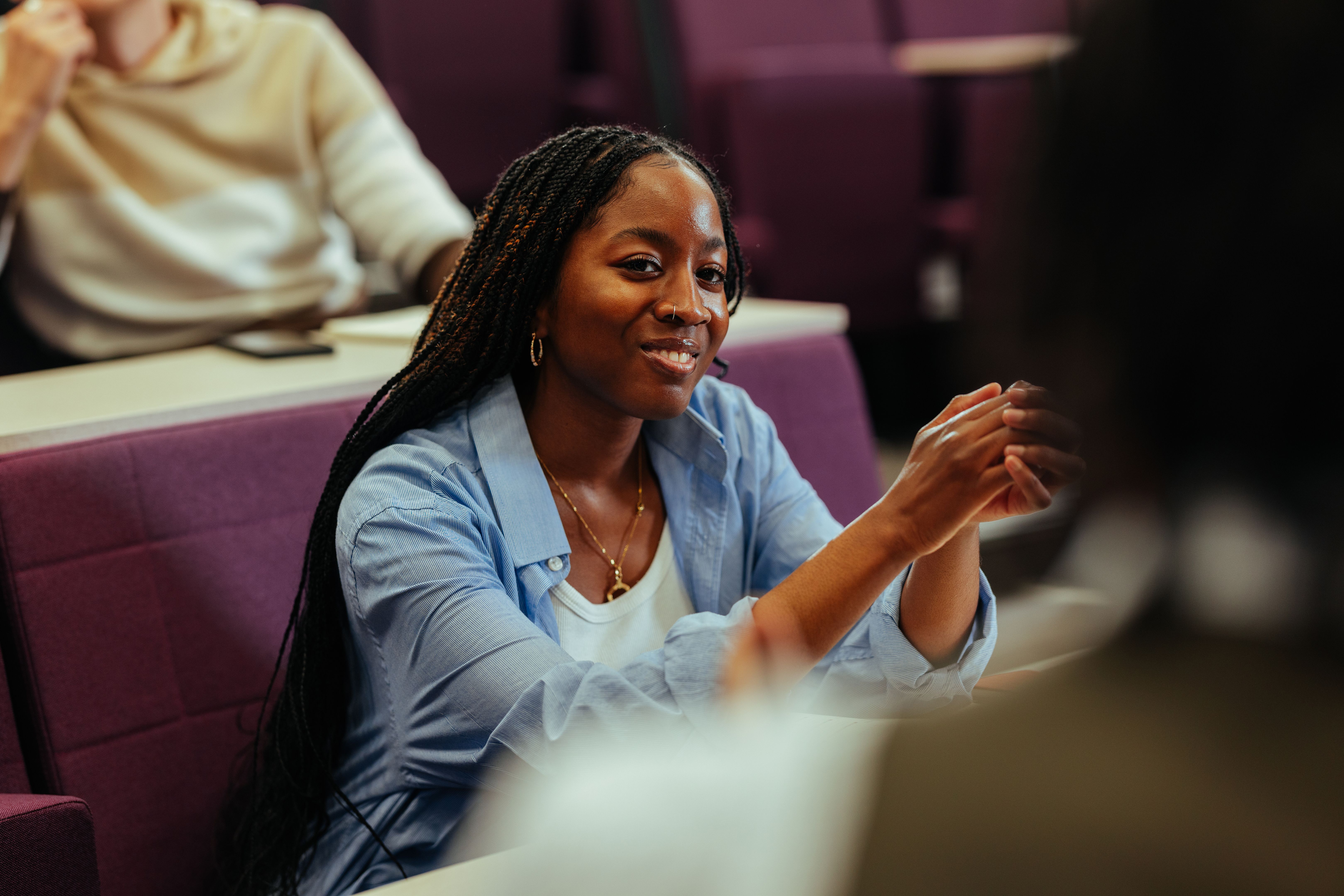 University student gesturing while talking with classmate in lecture hall University student gesturing while talking with classmate in lecture hall