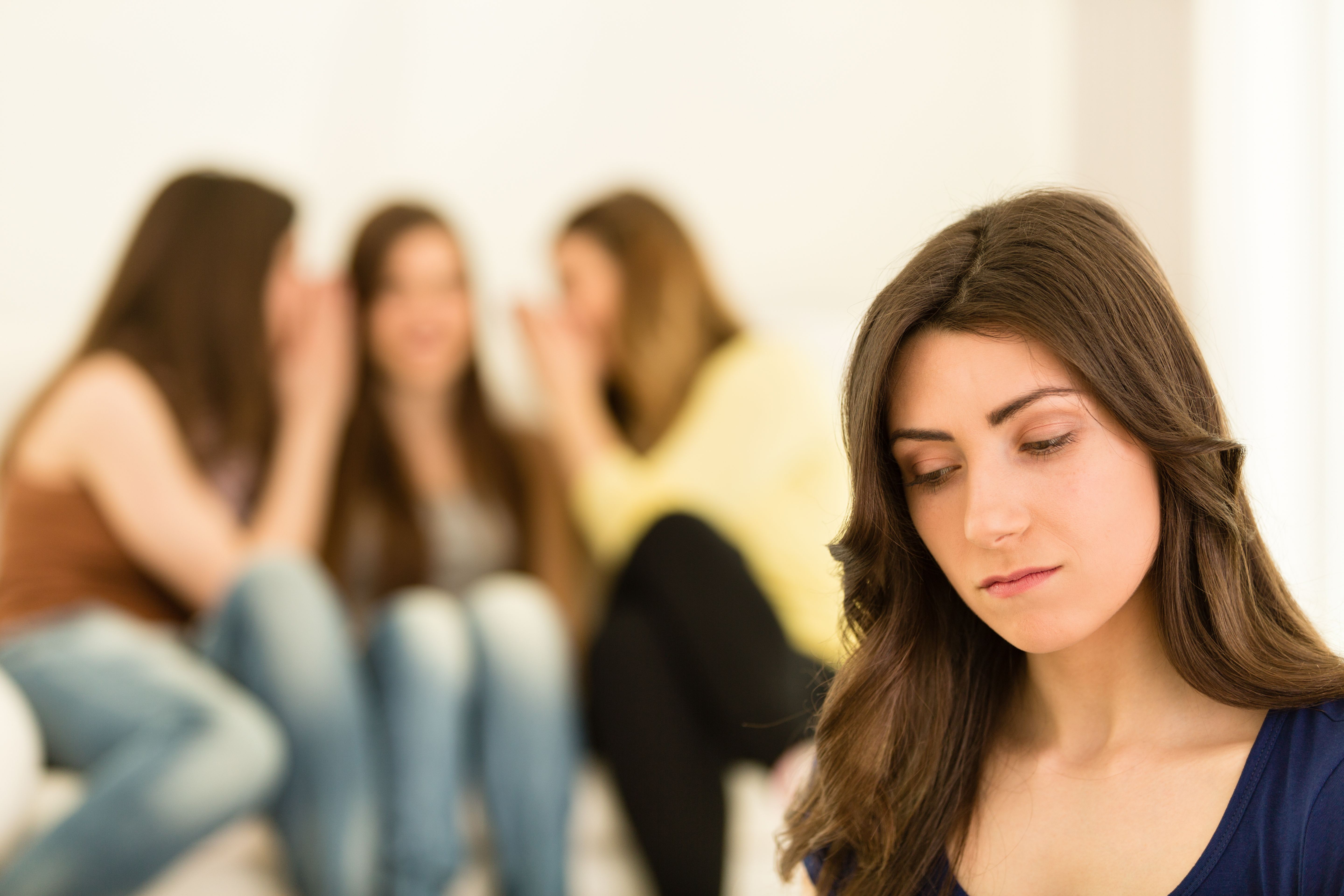 Girls in the background gossiping about another girl