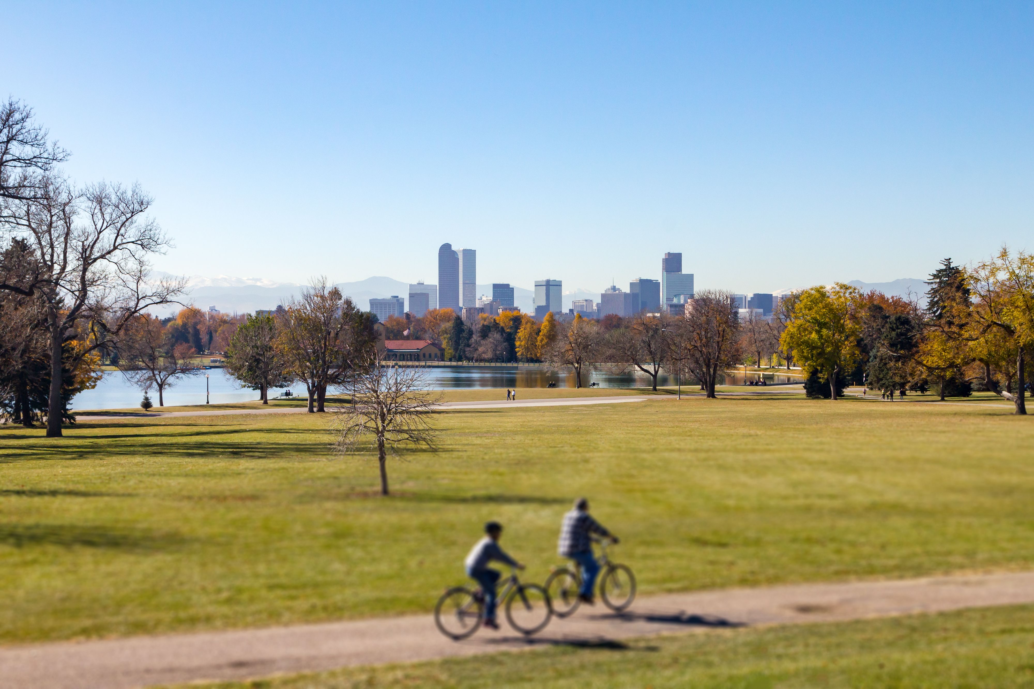 Denver Colorado downtown skyline with people riding bicycles on a trail through City Park