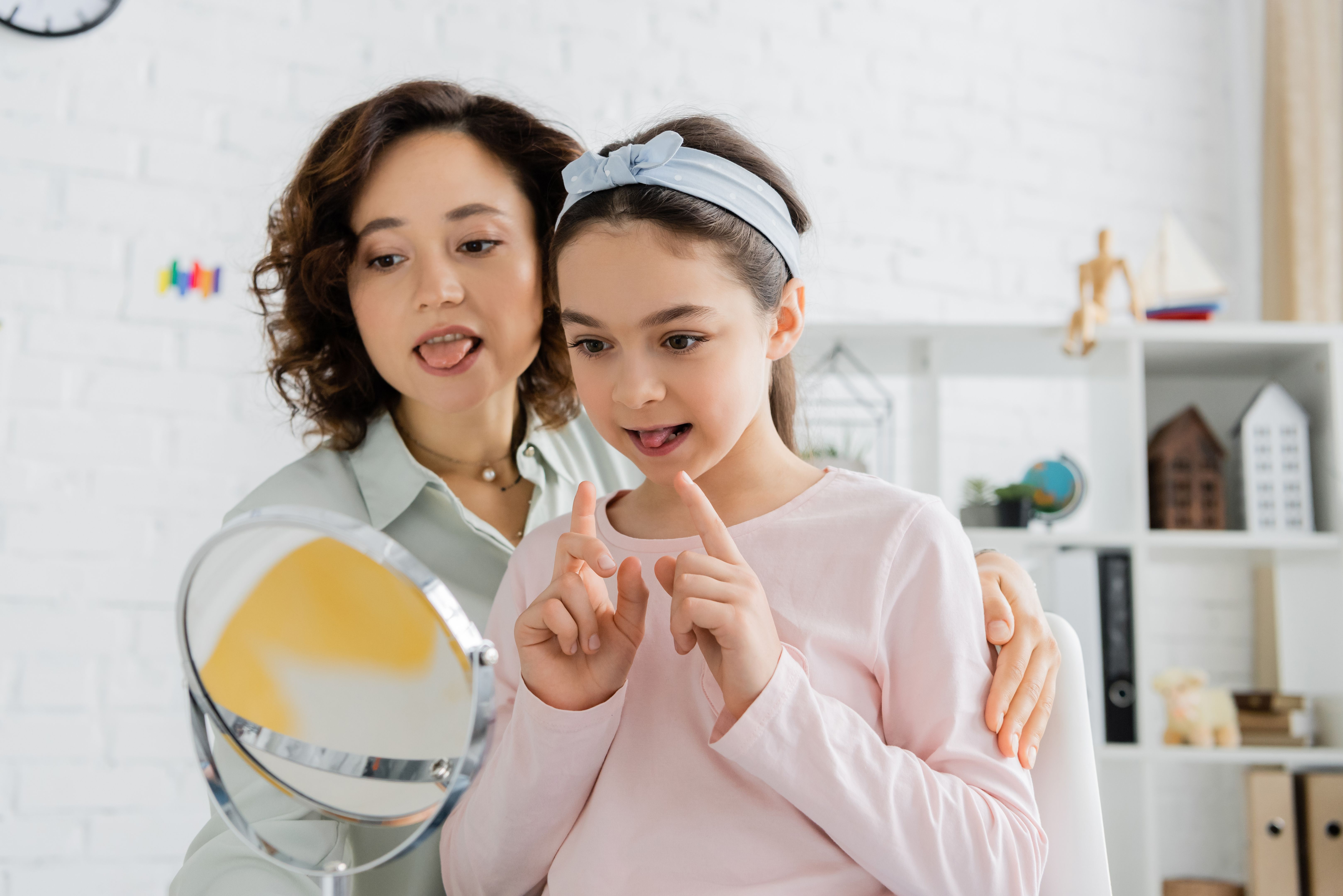 A speech therapist helps a child practice speaking in a bright consultation room