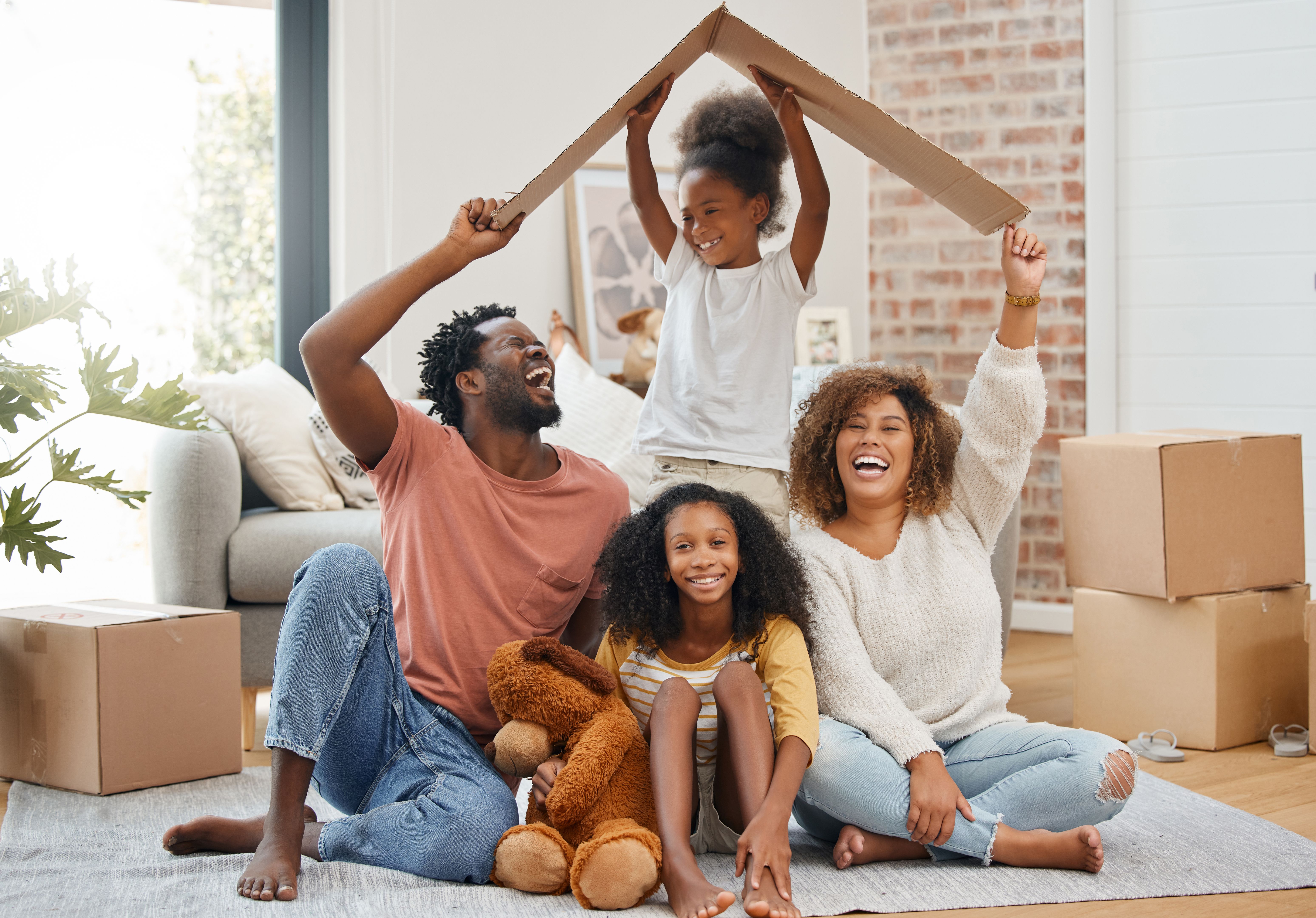 Shot of a young family holding up a cardboard box to form a roof at home Shot of a young family holding up a cardboard box to form a roof at home