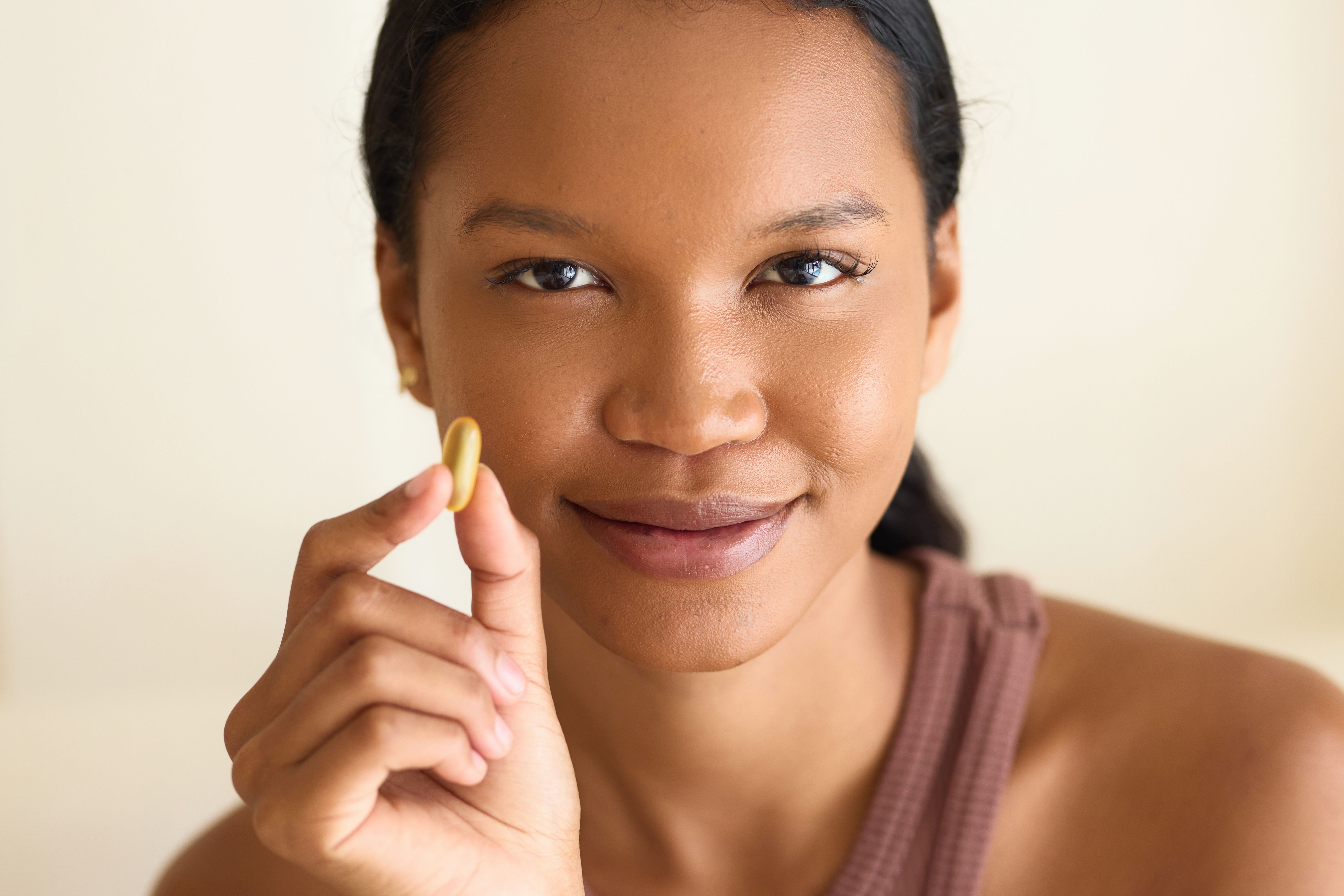 Young Woman Holding Vitamin Capsule for Healthy Skin and Nutrition