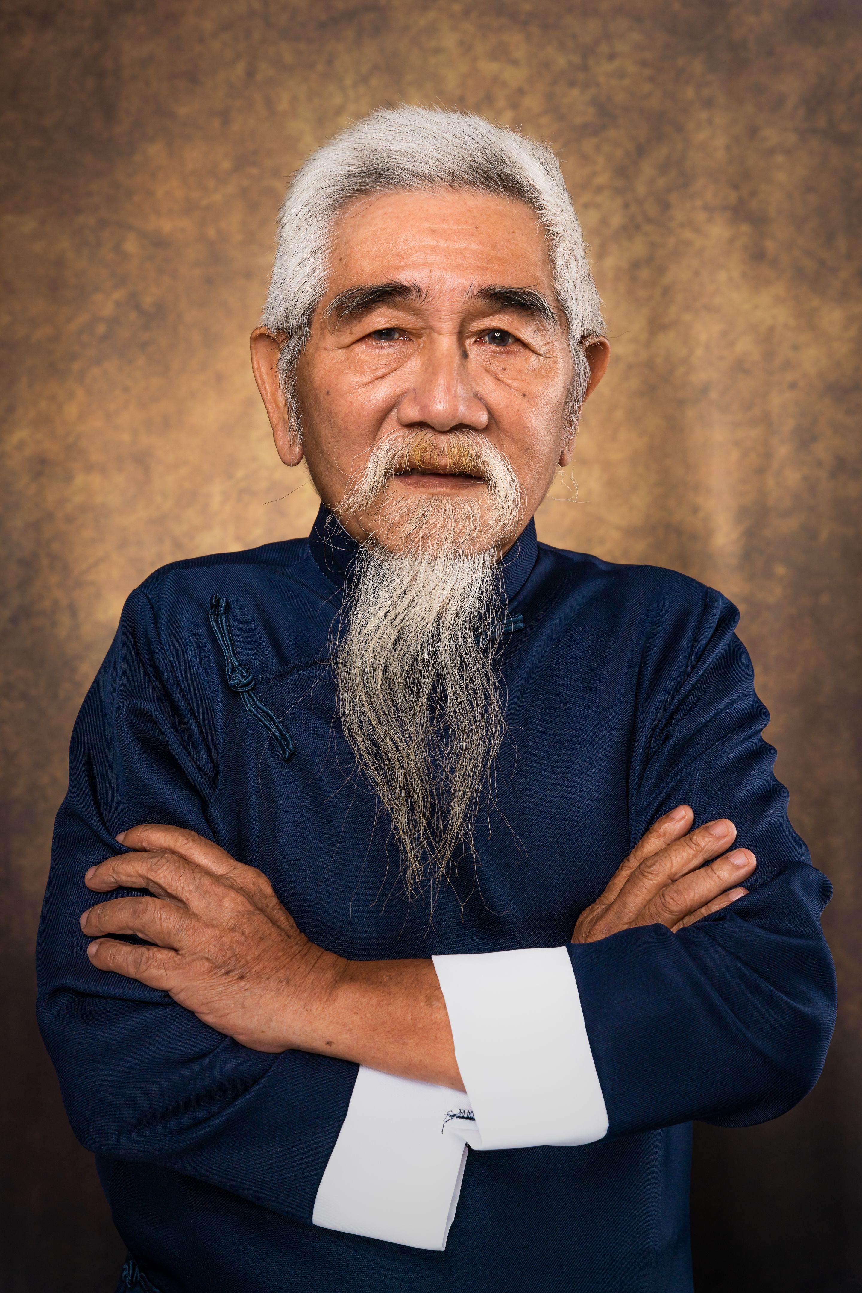 studio portrait of chinese old man with white hair and beard in traditional chinese clothing on studio backdrop background