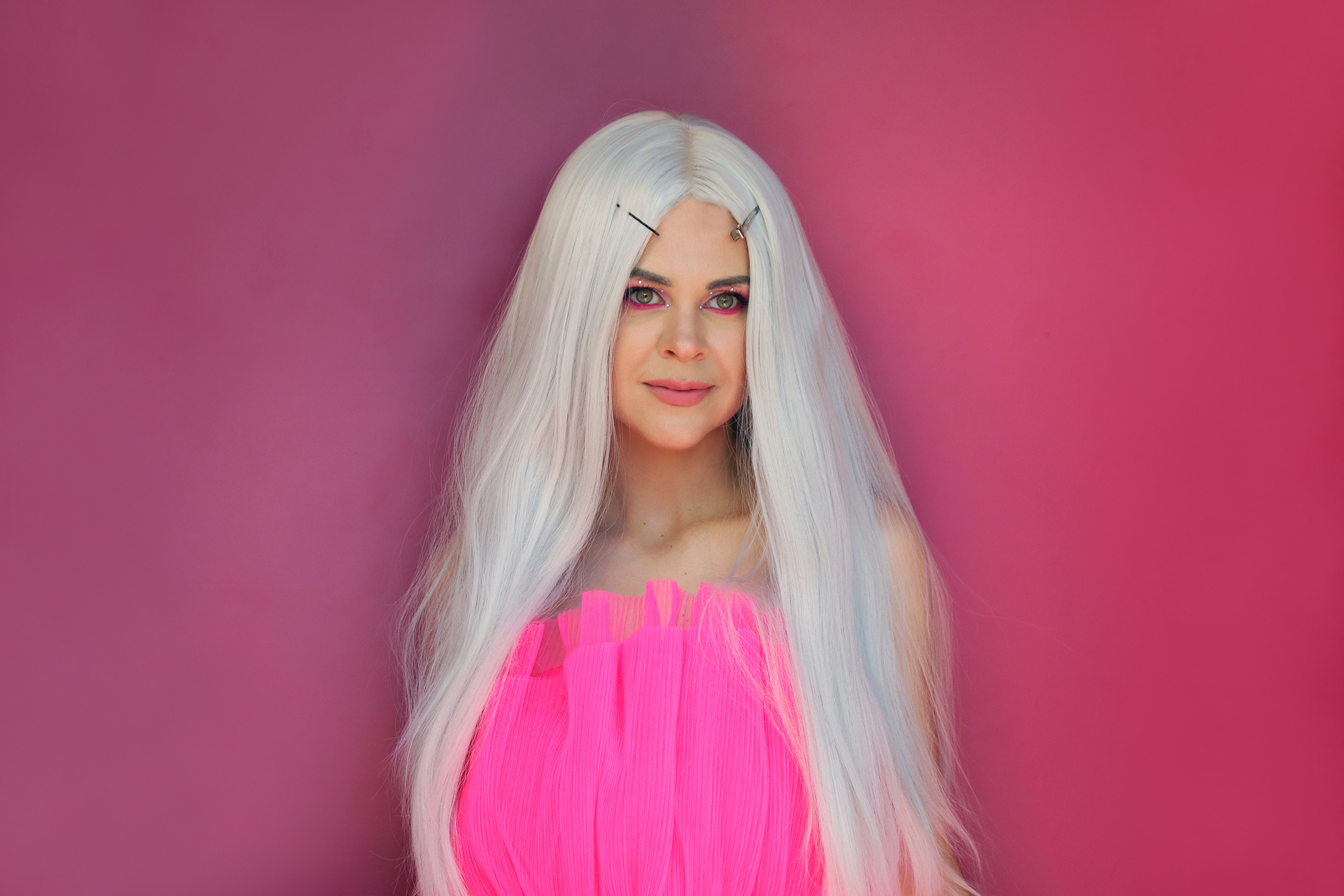 Stylish young blonde girl look like fashion doll in pink dress on pink background. Beauty concept. Youth Culture. Blond girl doll