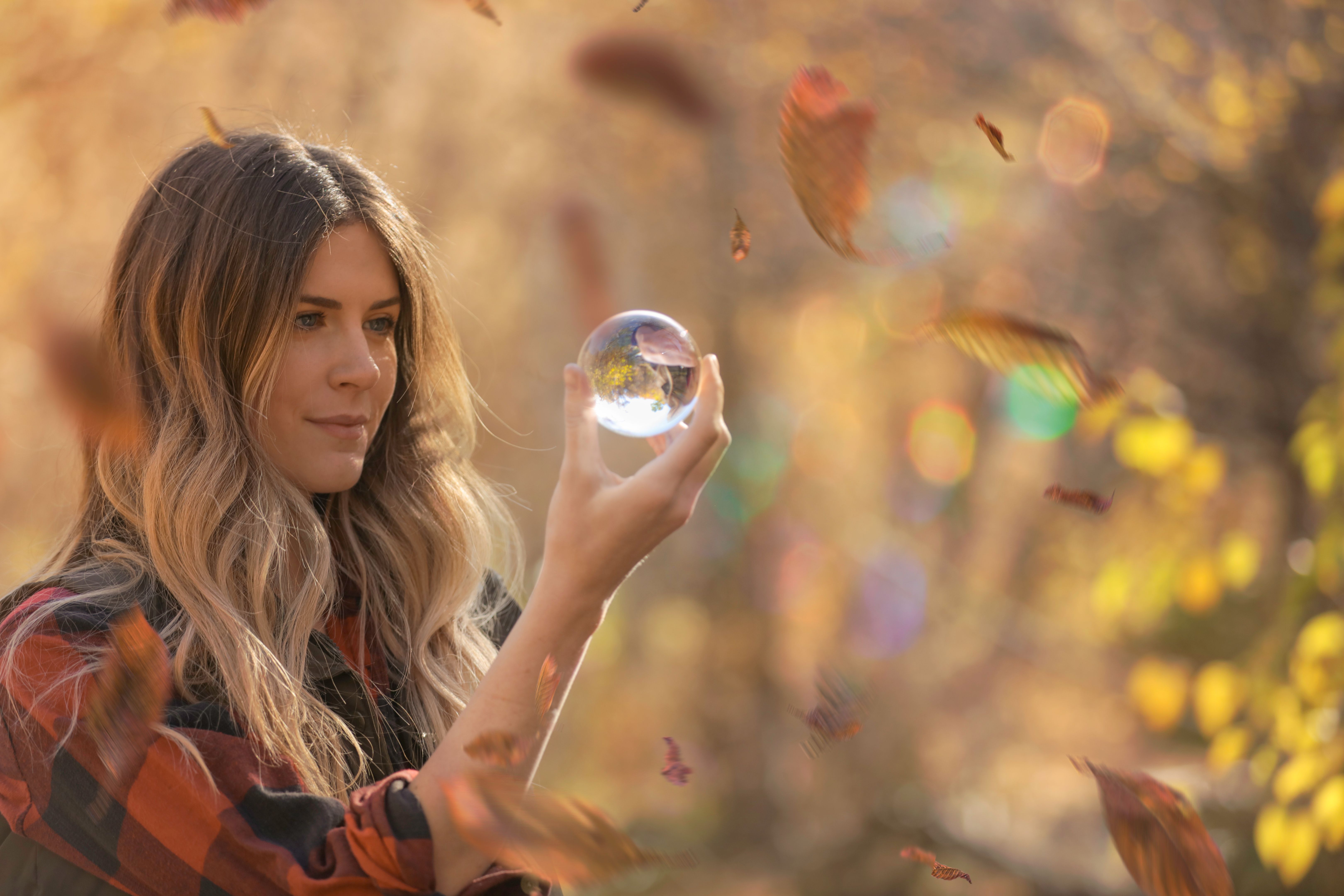 Woman hiking near stream looking into glass ball