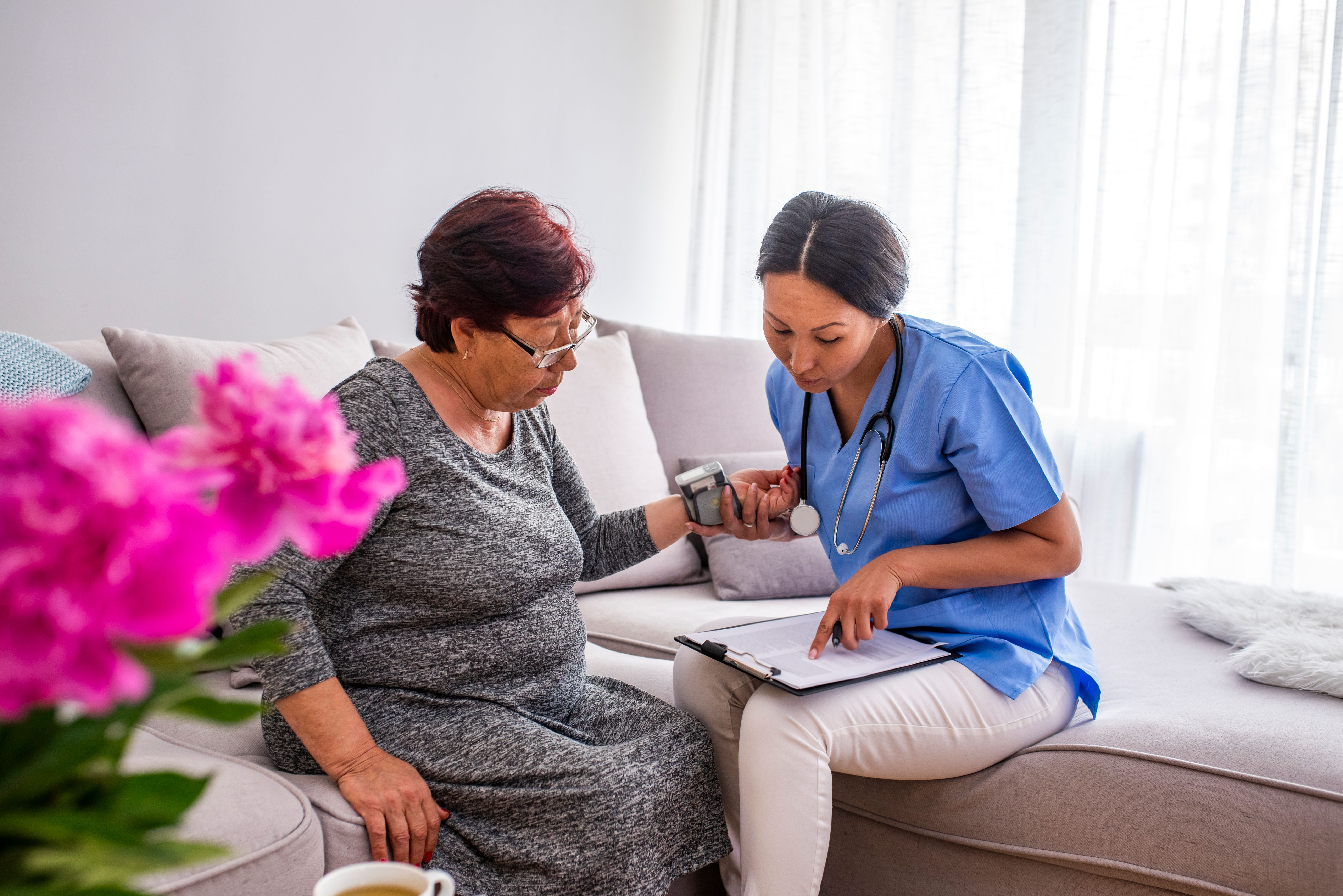 Asian nurse doing blood pressure monitoring for senior woman at home Asian nurse doing blood pressure monitoring for senior woman at home