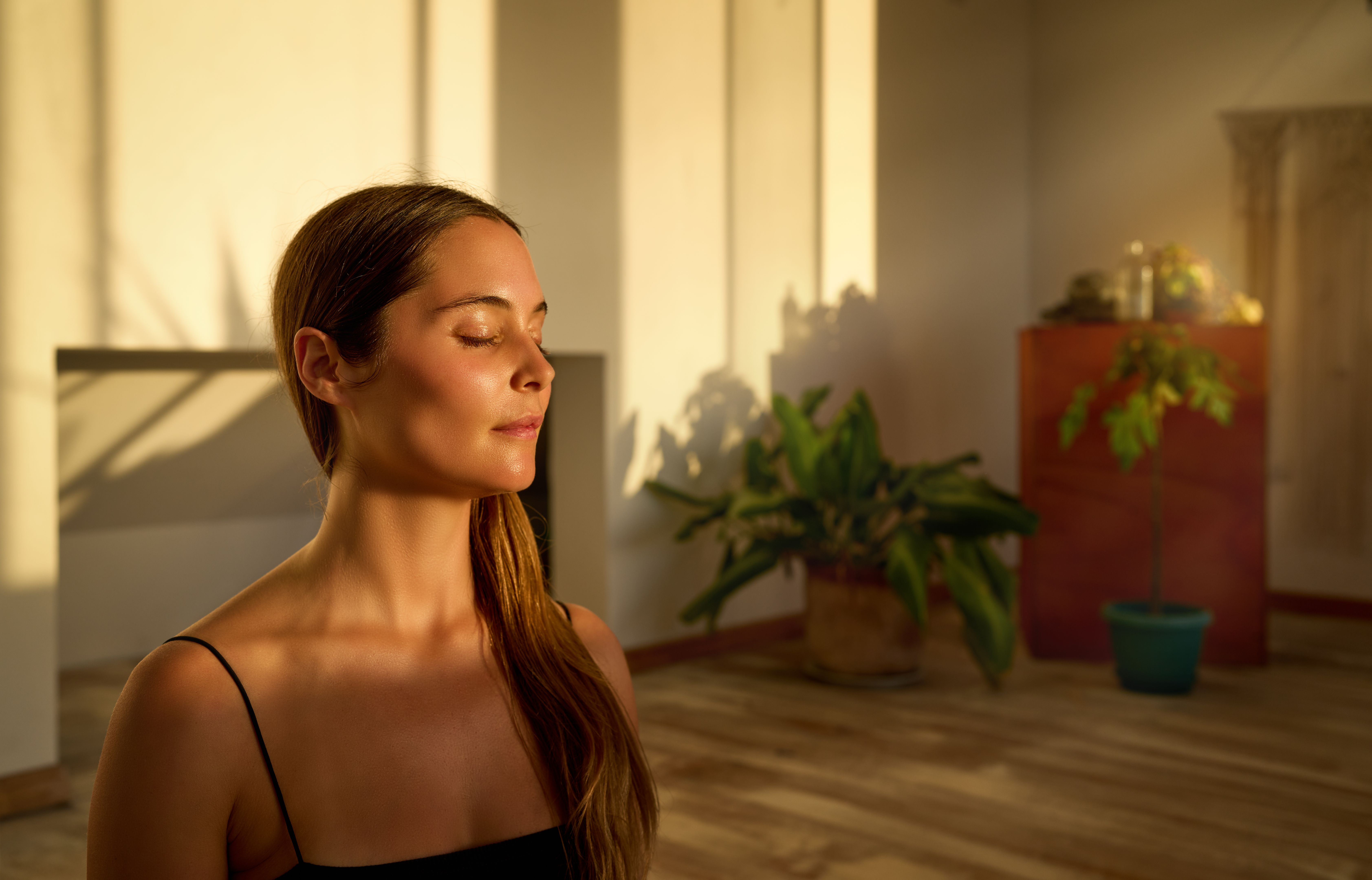 portrait young caucasian woman sitting with closed eyes meditating indoors