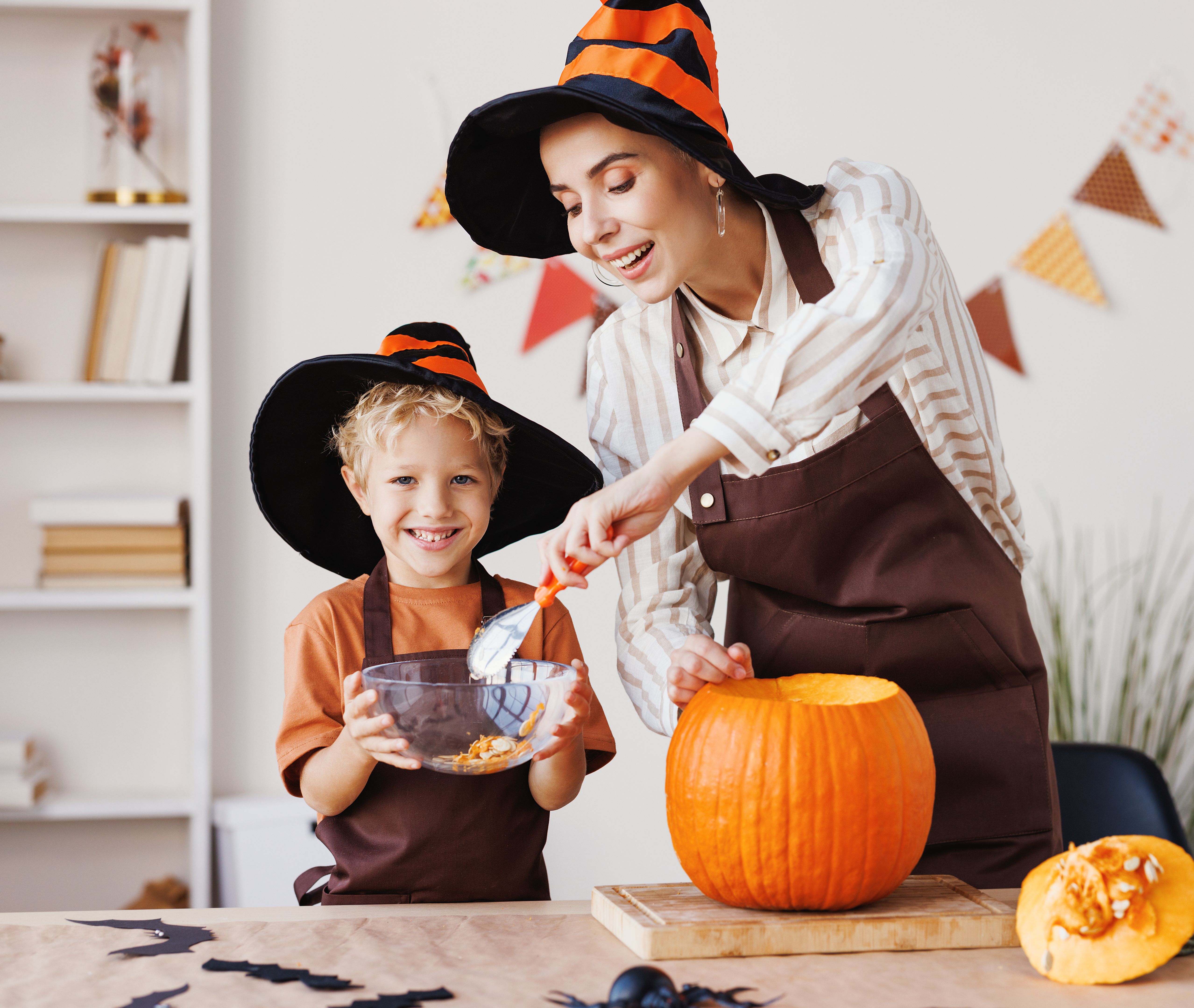 Son and mom making Jack-o-Lantern together at home, carving Halloween pumpkin Son and mom making Jack-o-Lantern together at home, carving Halloween pumpkin