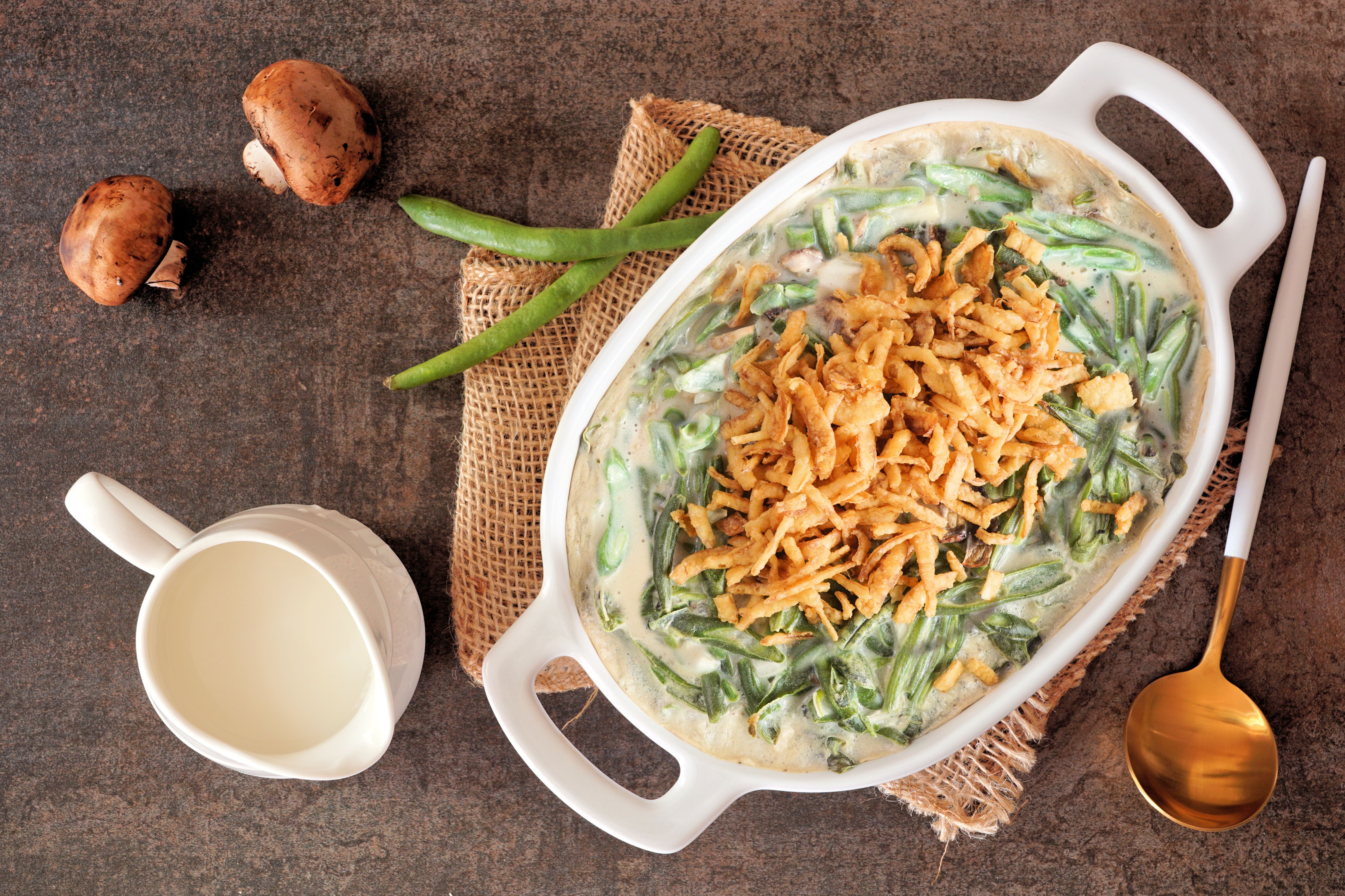 Traditional homemade green bean casserole. Overhead view table scene on a dark stone background.