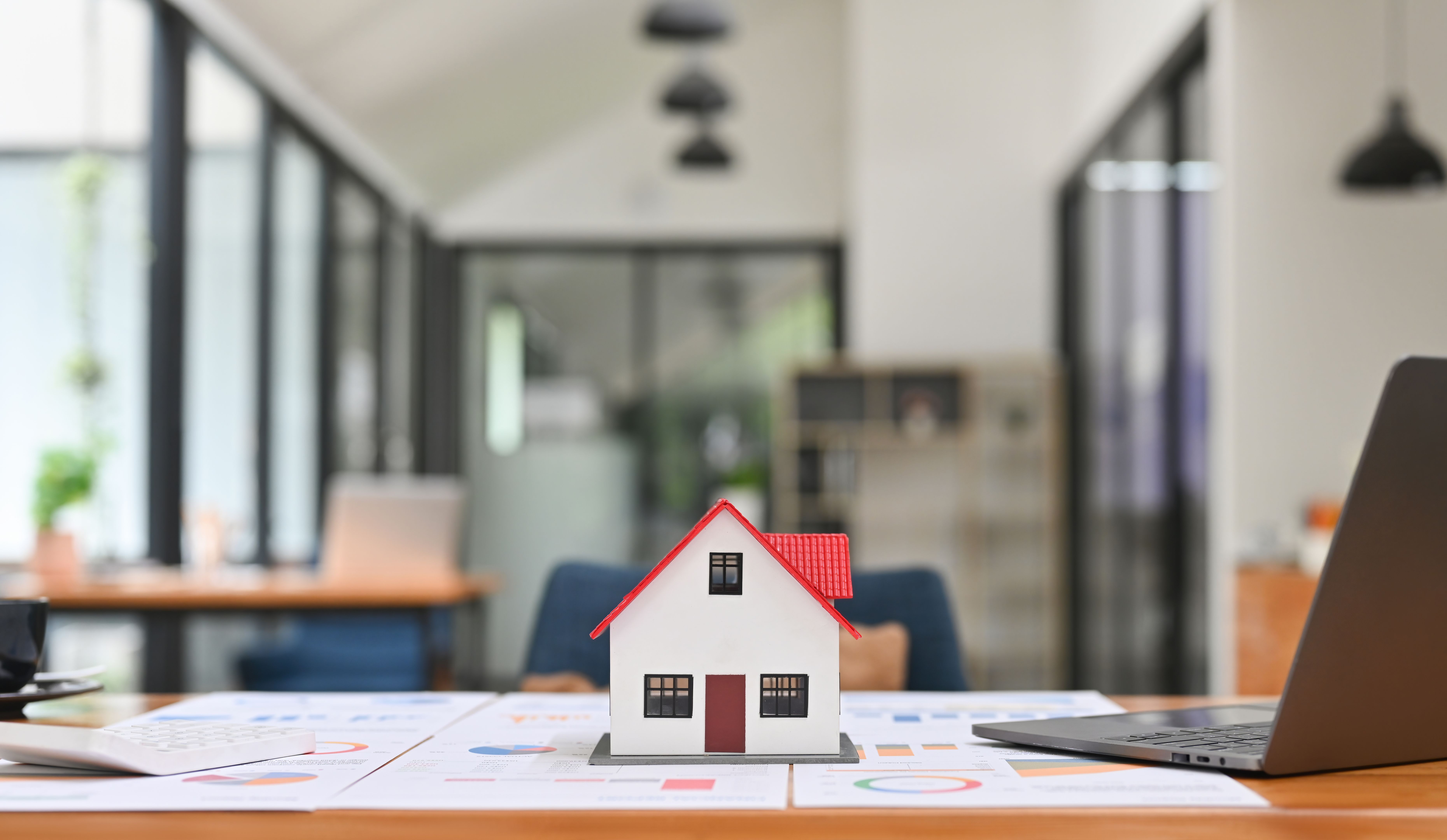 Financial planning, investment, real estate, residential house concept. Close up of mockup house and key placed on home brokers desk.