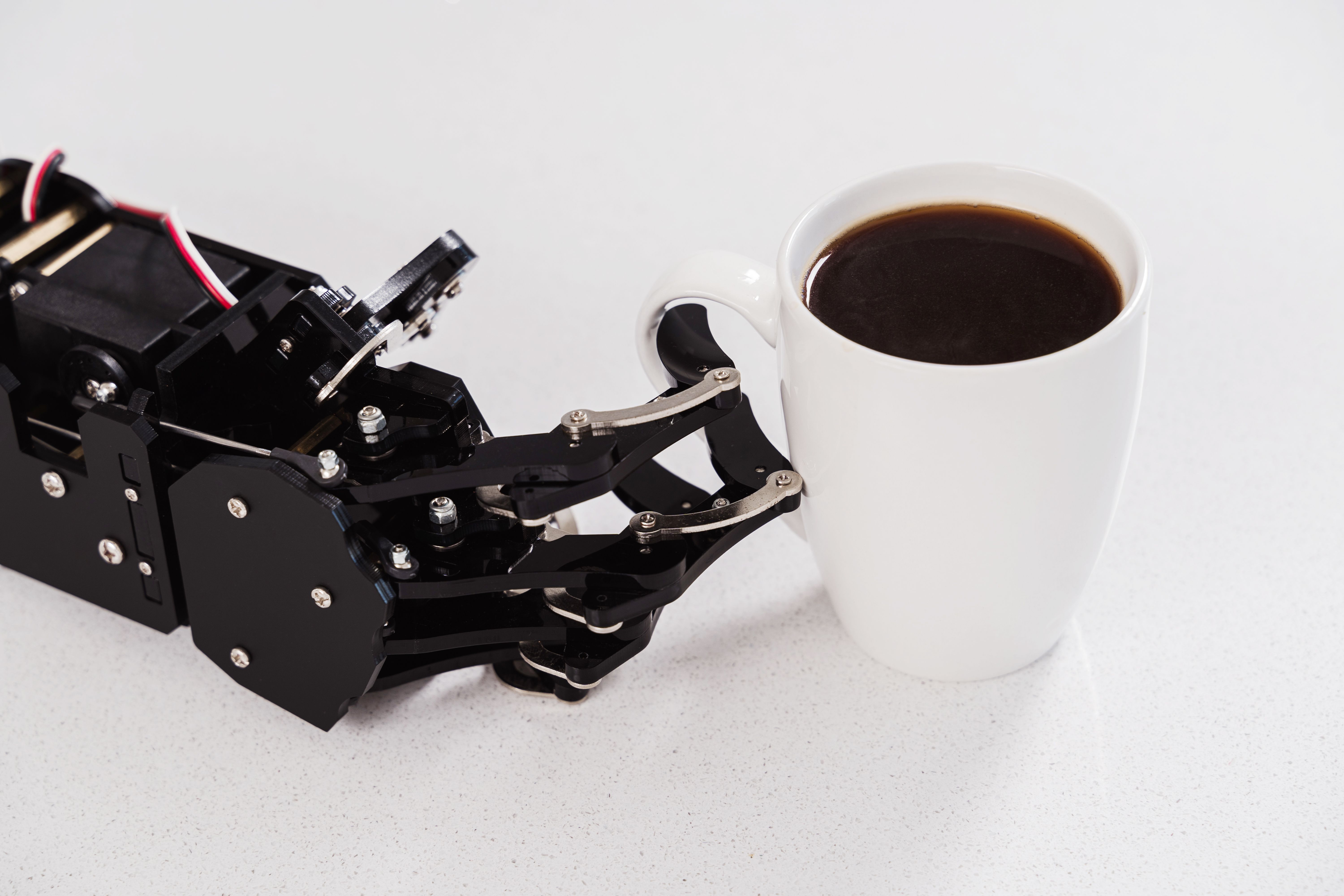Real robot hand  and white cup of coffee. Concept of  robotic process automation