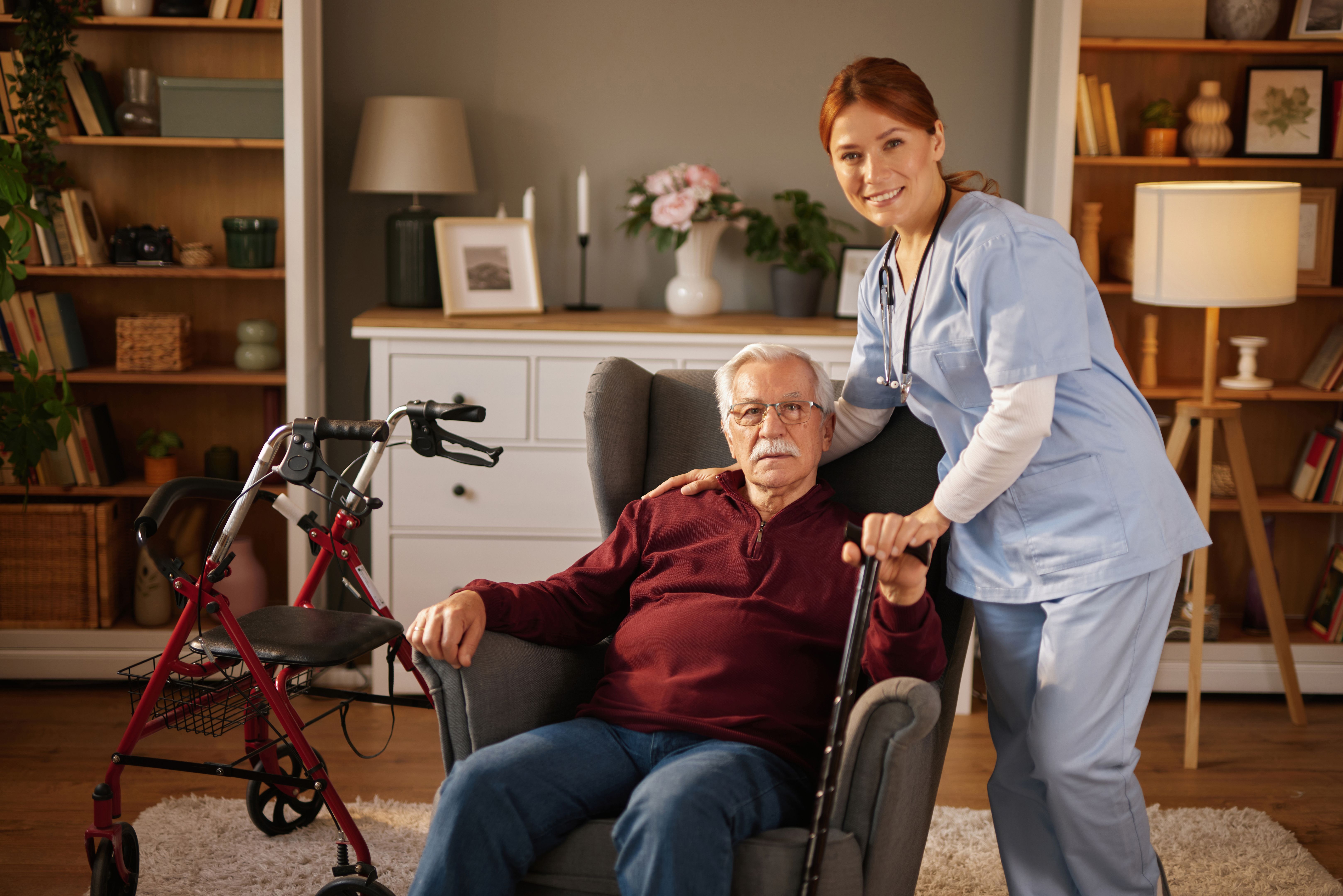 Home healthcare nurse smiling and assisting elderly man in his living room