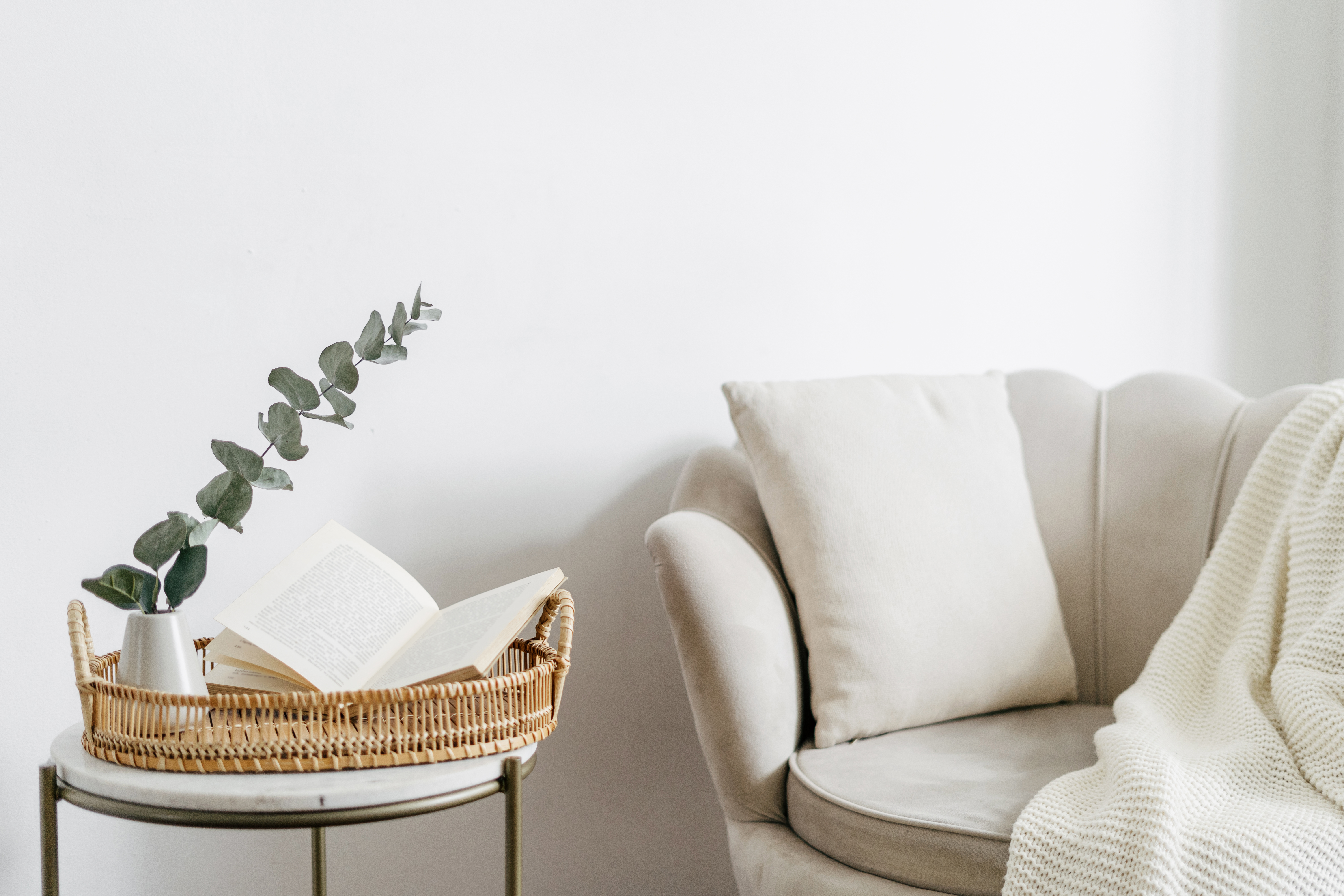 Libro abierto en bandeja en la habitación, cerca de sillón beige con almohada