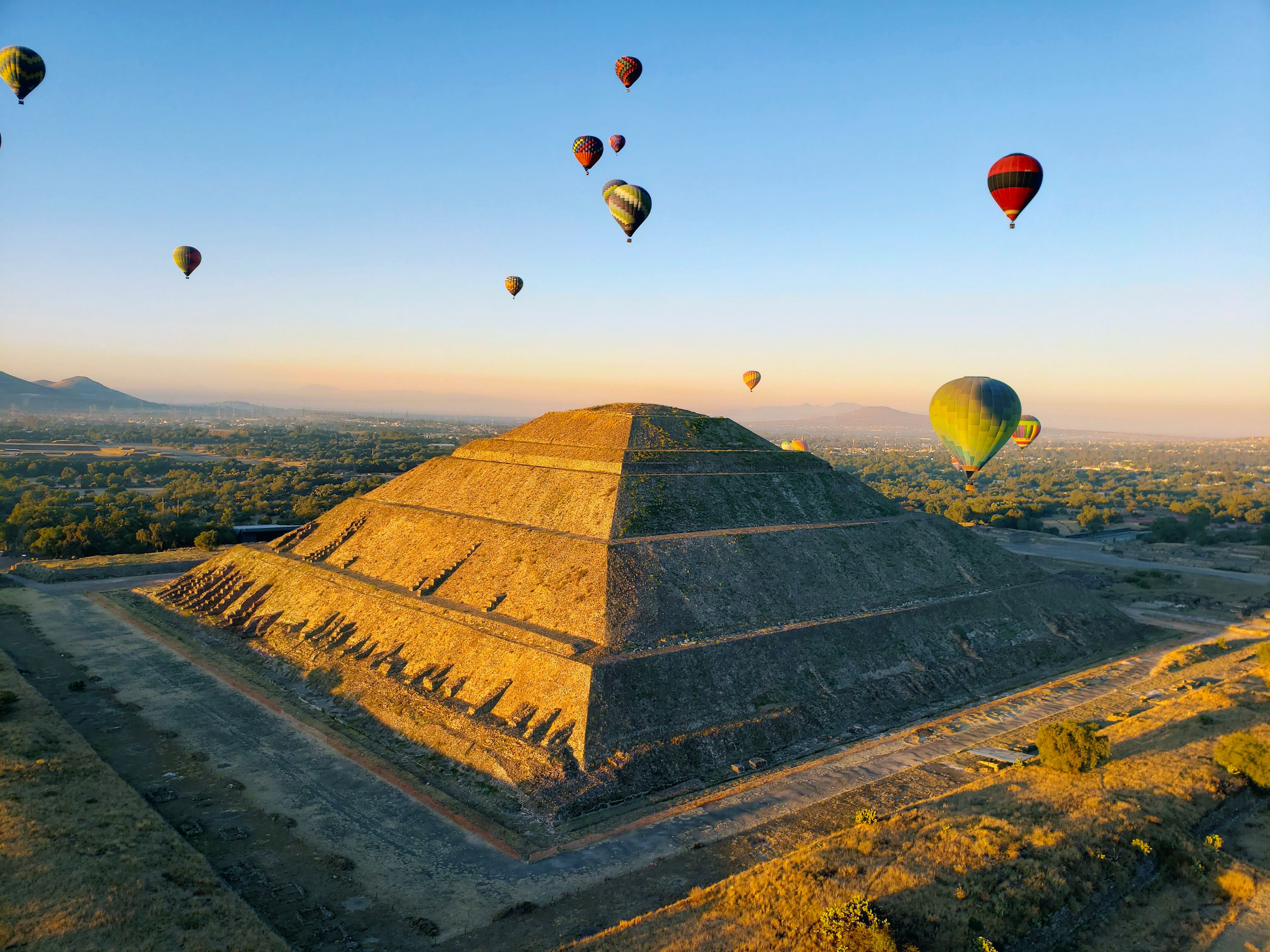 Hot air balloons in the sky flying above Teotihuacan in Mexico, aerial view, blue sky, sunrise, Mexican pyramid