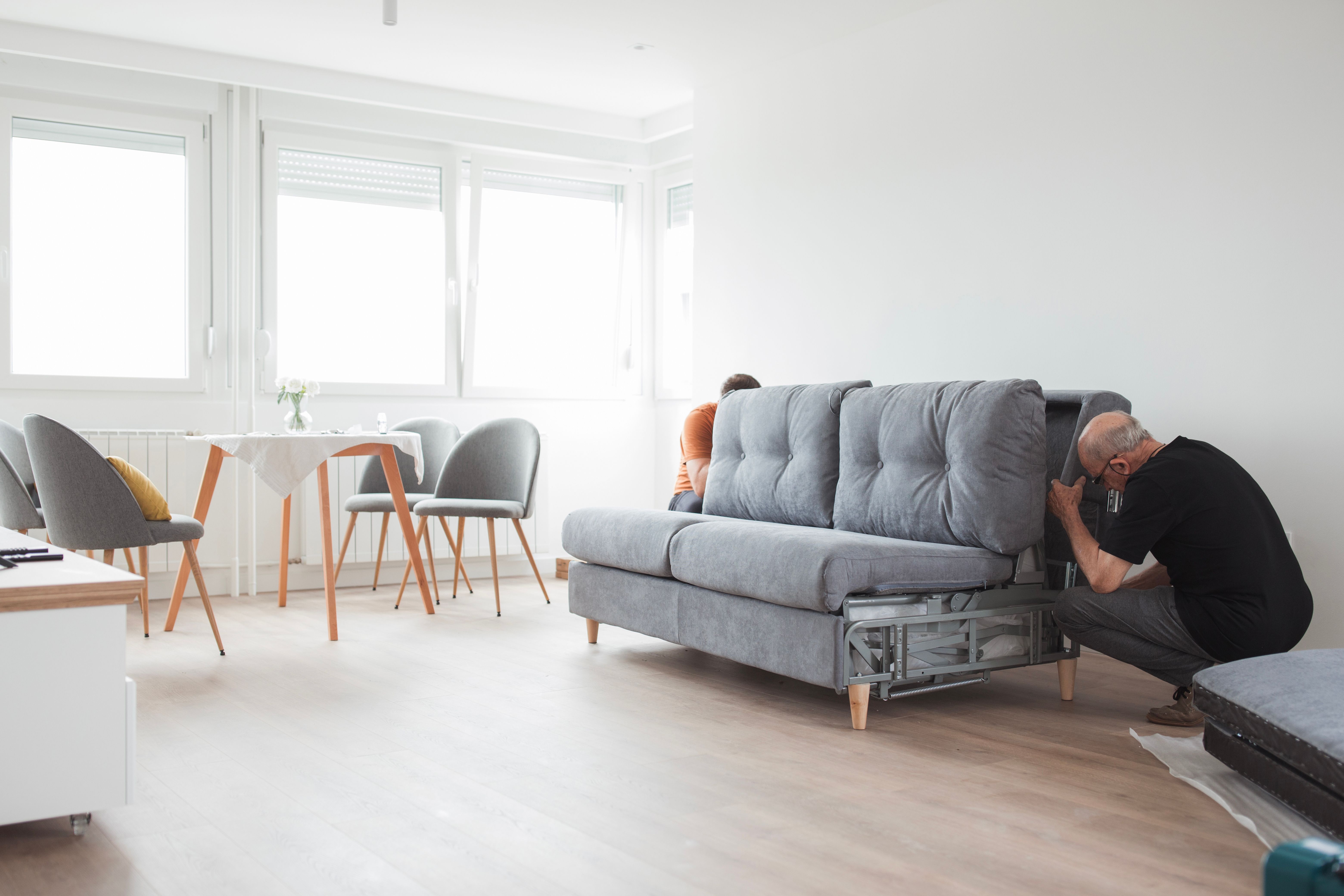 Men pushing and assembling new sofa at home