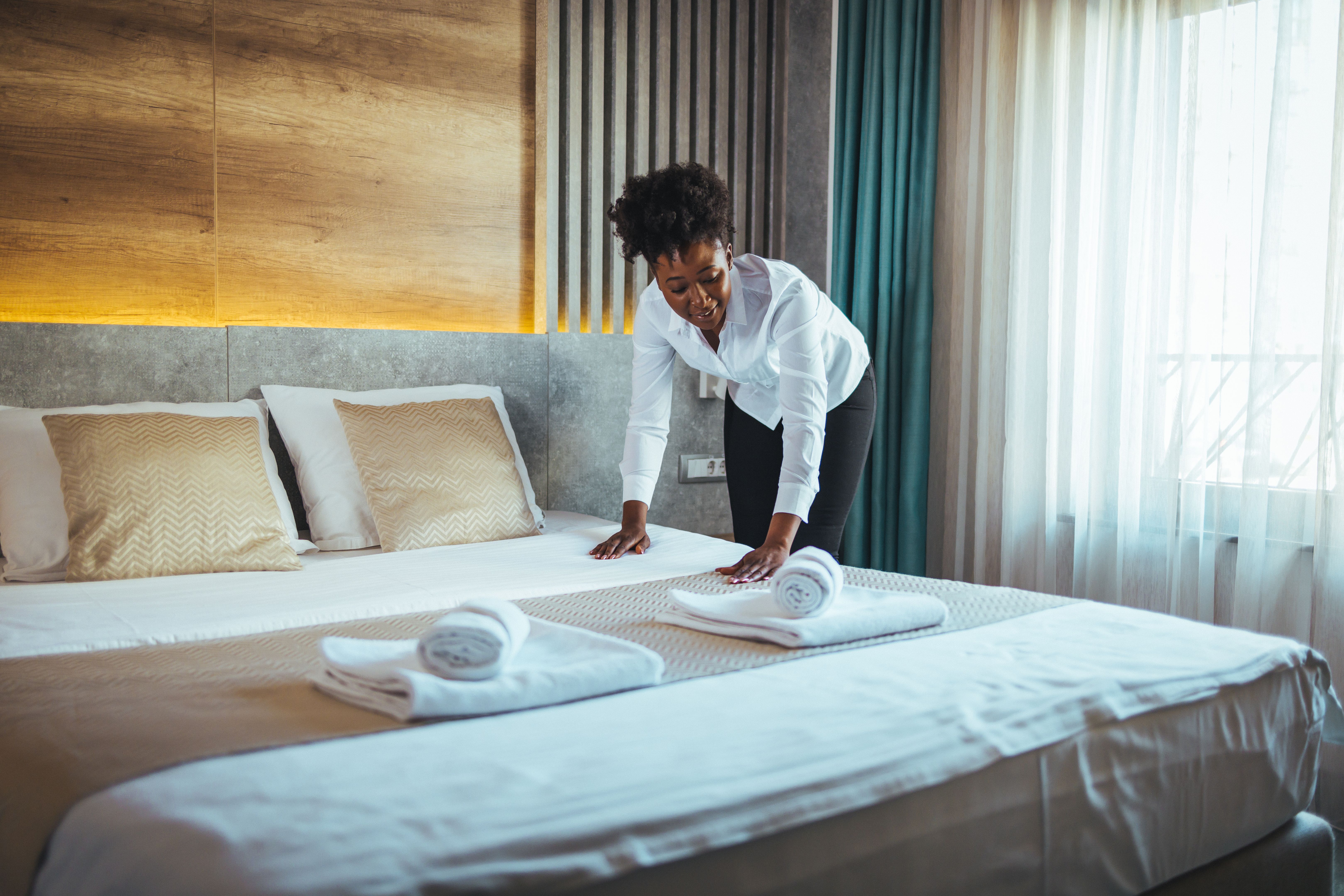 Maid working making the bed at a hotel.