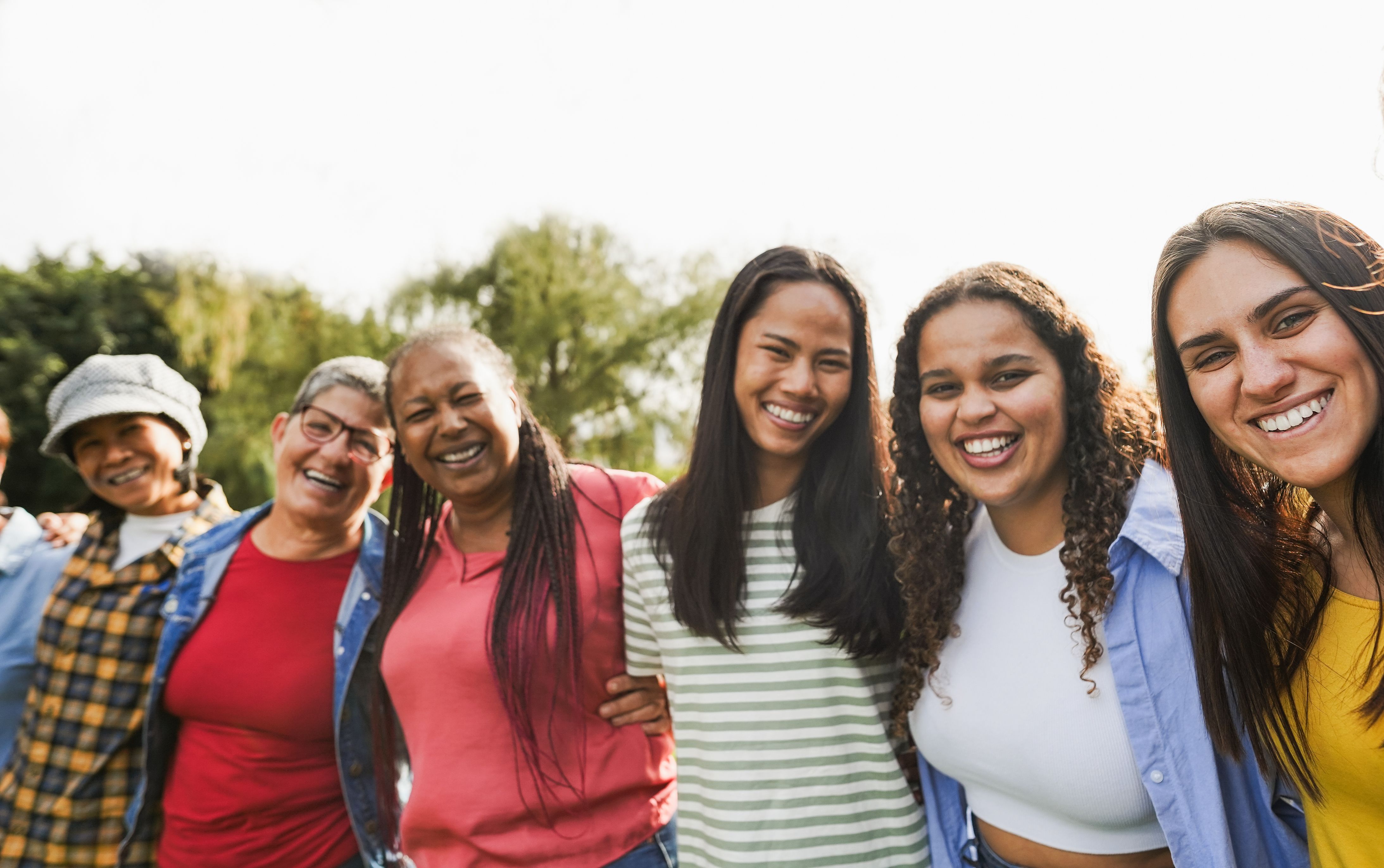 Multi generational women smiling in front of camera - Female multiracial group having fun togheter outdoor - Main focus on right girl face