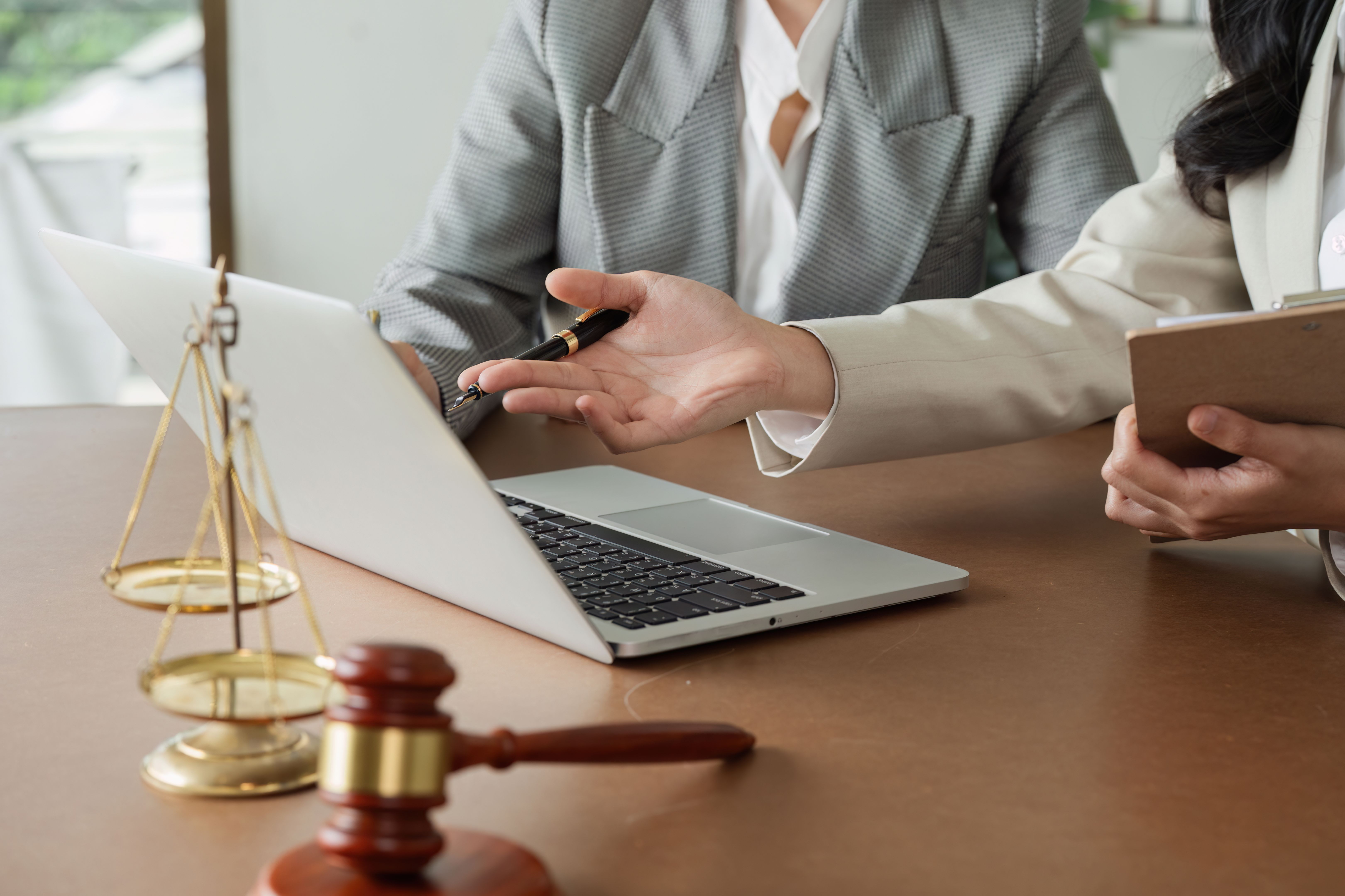 Lawyer and client discuss data on laptop, advise client on business matters on laptop