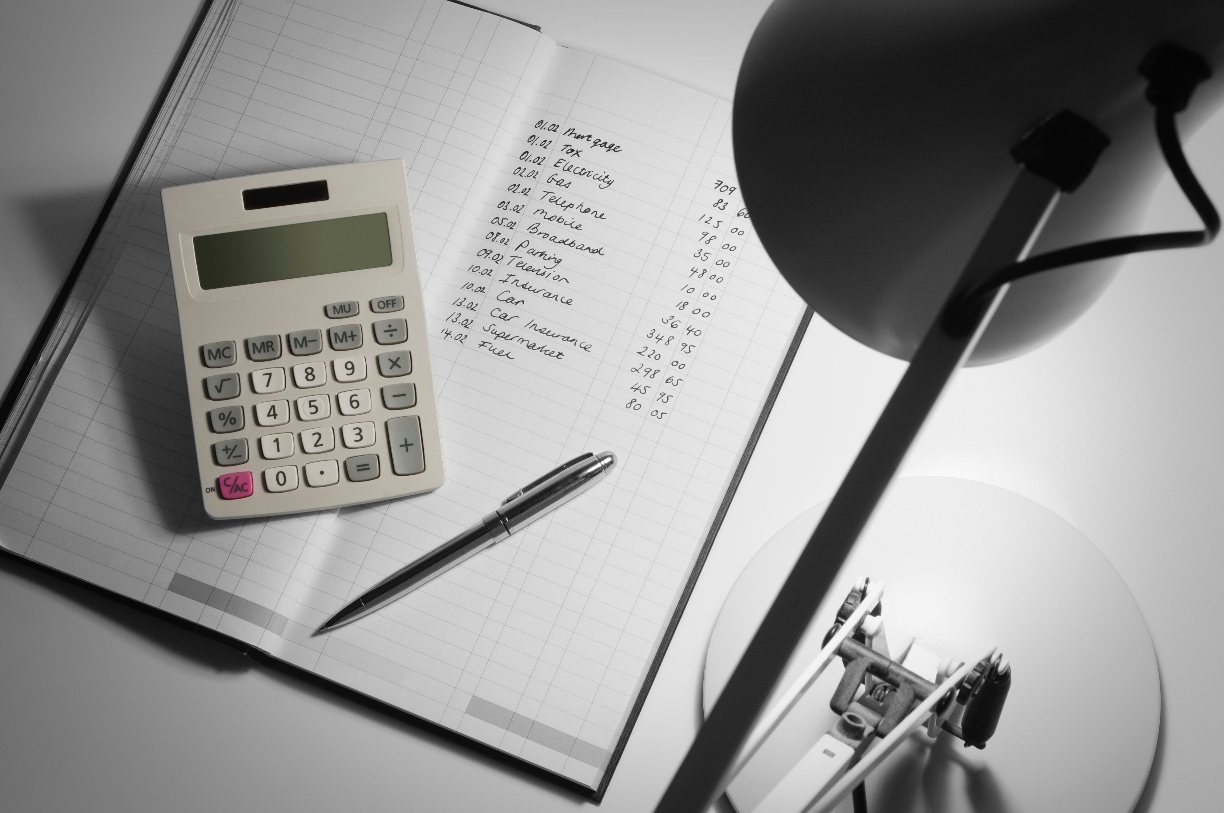 Desk lamp over book keeping journal and calculator