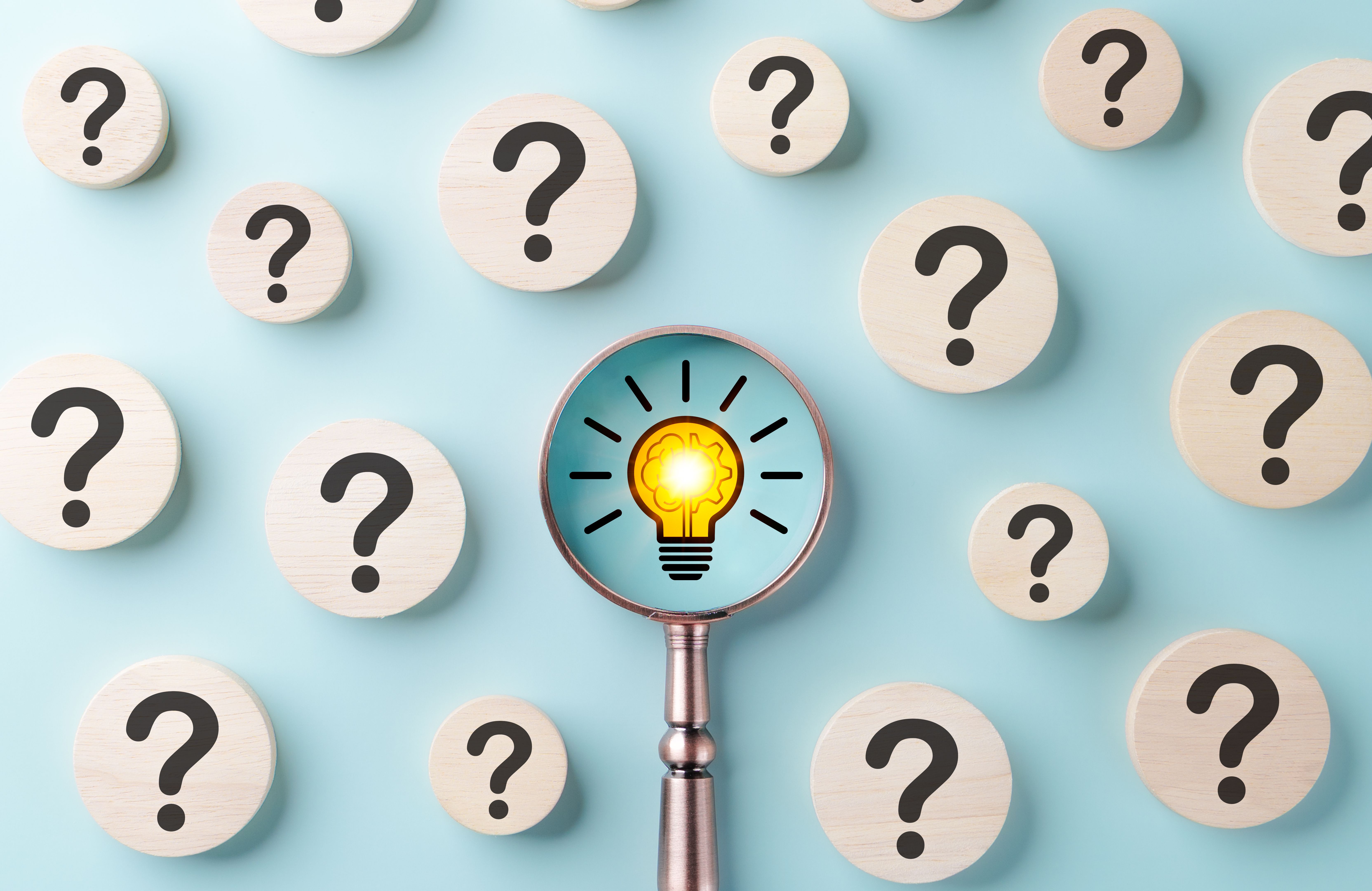 Finding Solutions Among Questions. Question marks on blue background, while magnifying glass focuses glowing light bulb, discovery of innovative solution, root cause analysis, ideas on problem solving