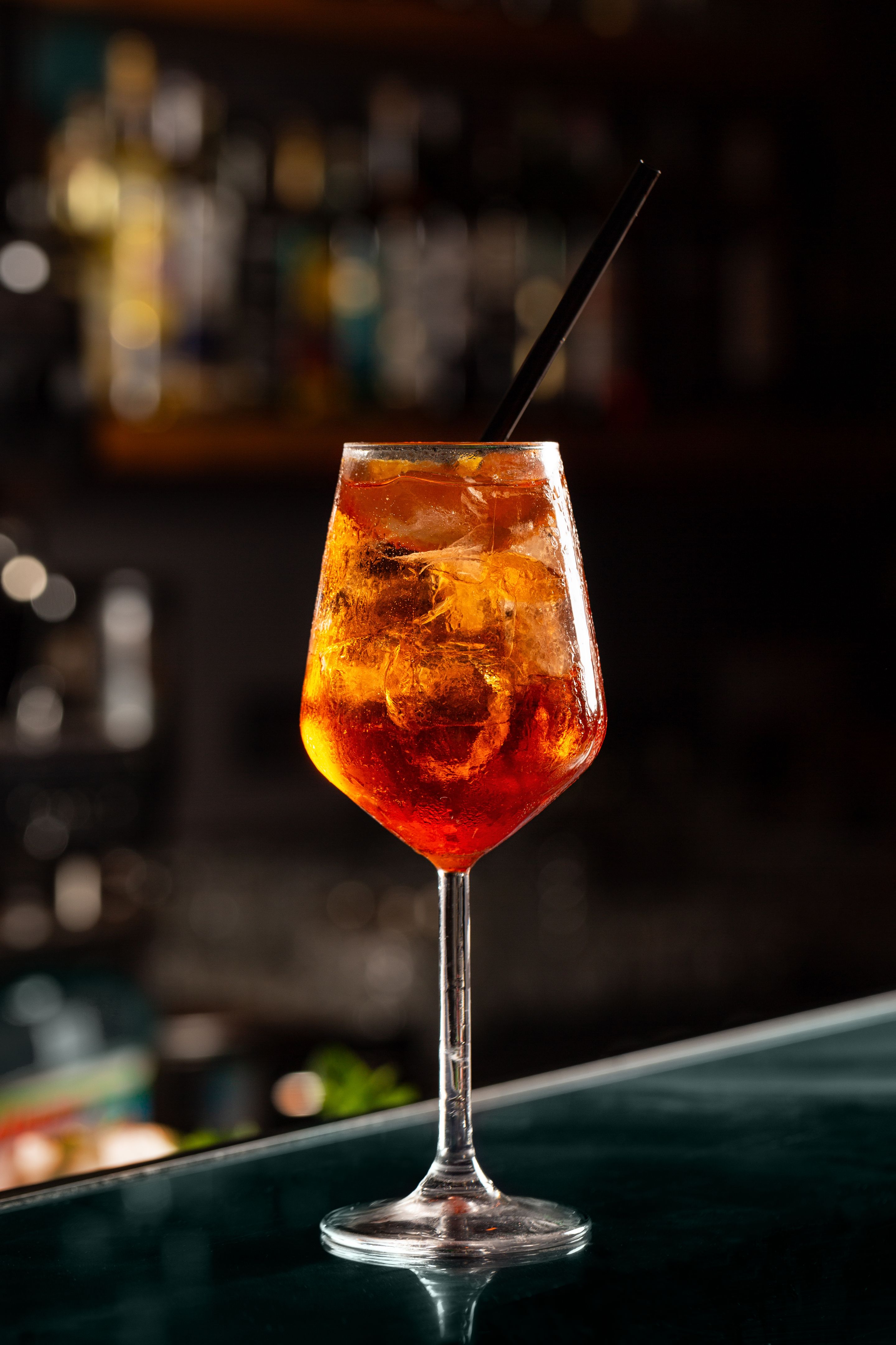 Close up of cold drink in a dark night bar, italian spritz, wine-based cocktail, consists of Prosecco wine, digestive bitters, soda water and oranges.