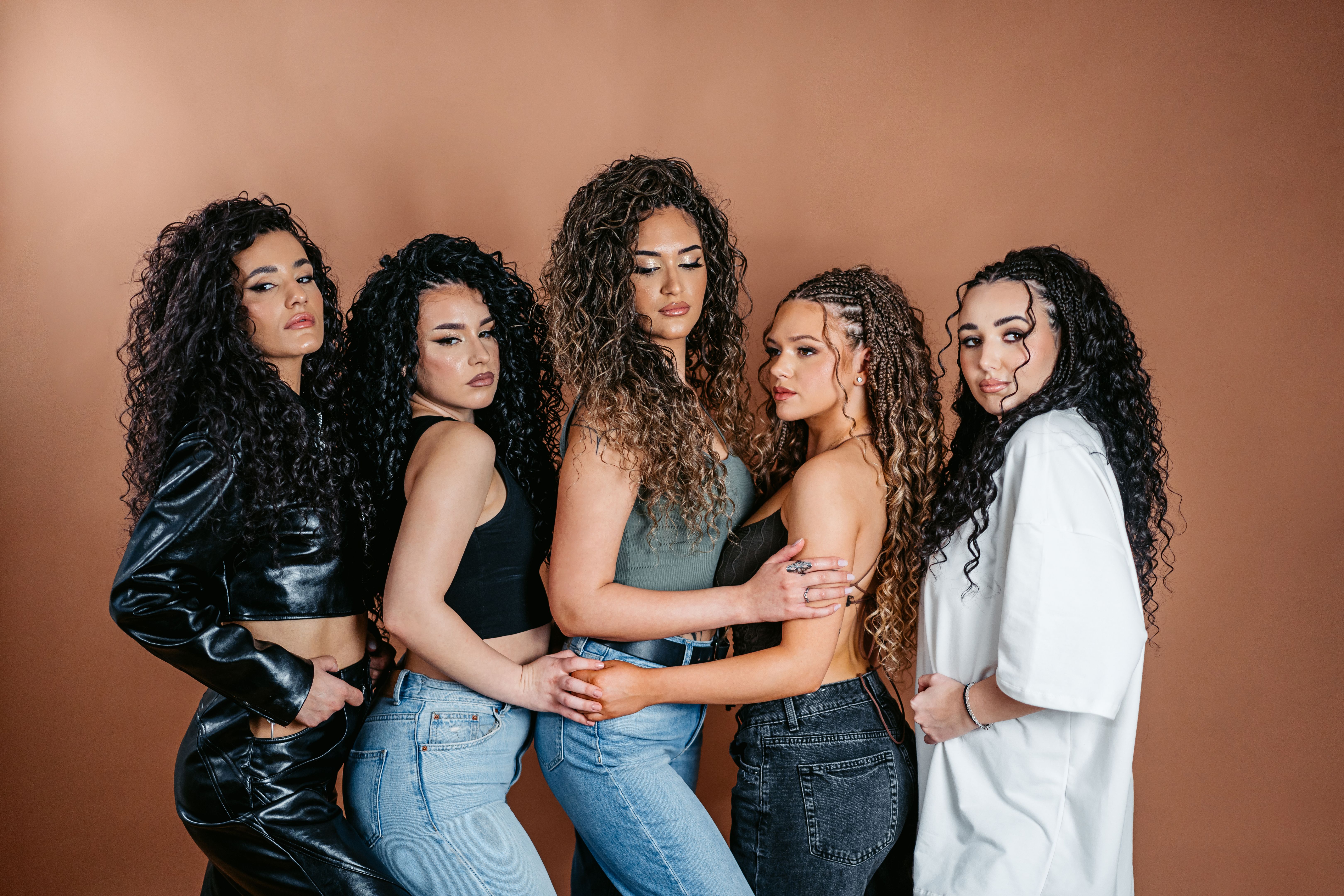 Portrait Of Five Curly Women Against A Brown Background