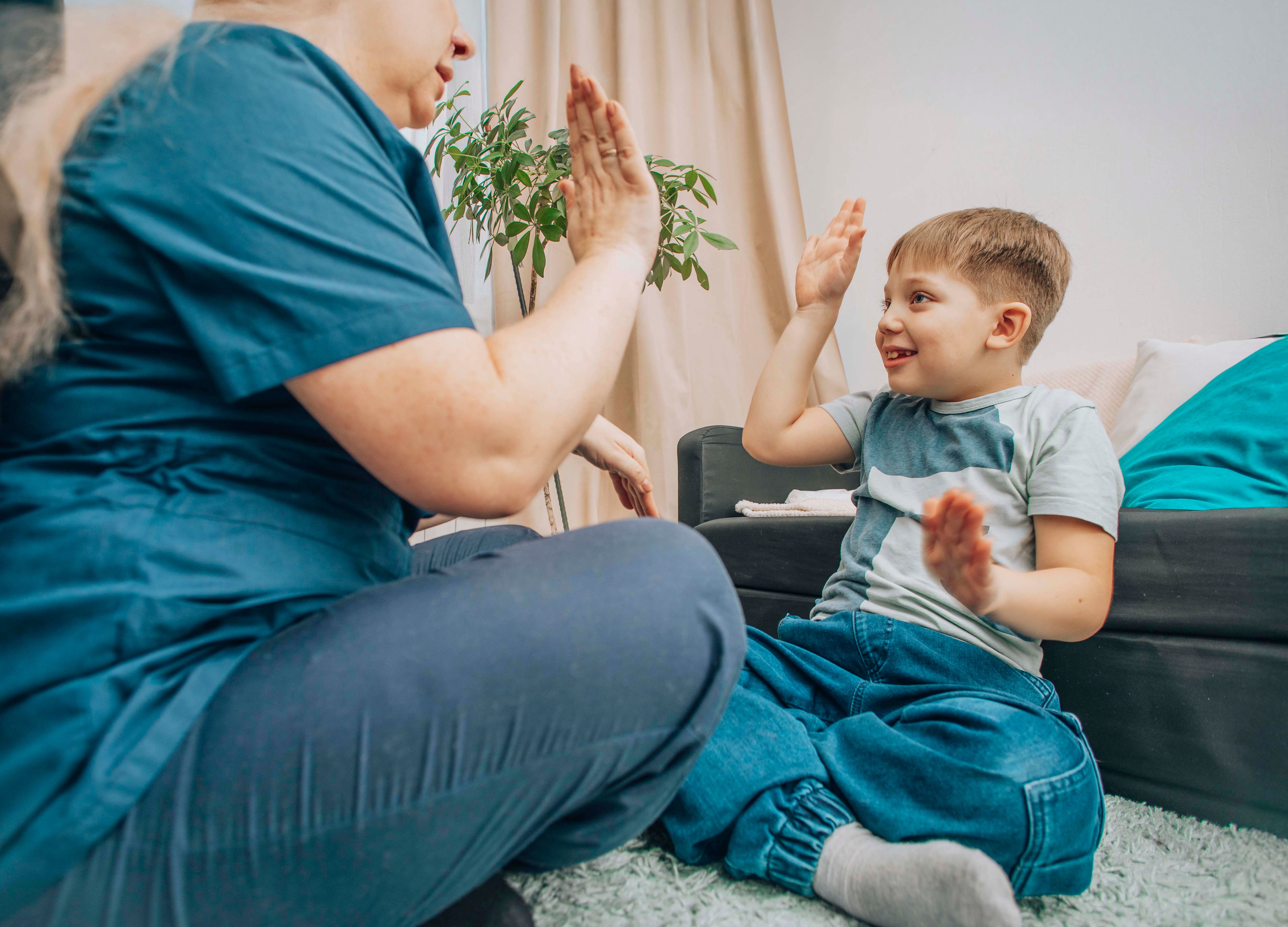 speech therapist engaging with young boy in nonverbal communication training, living room with warm decor, concept of education and cognitive skills development