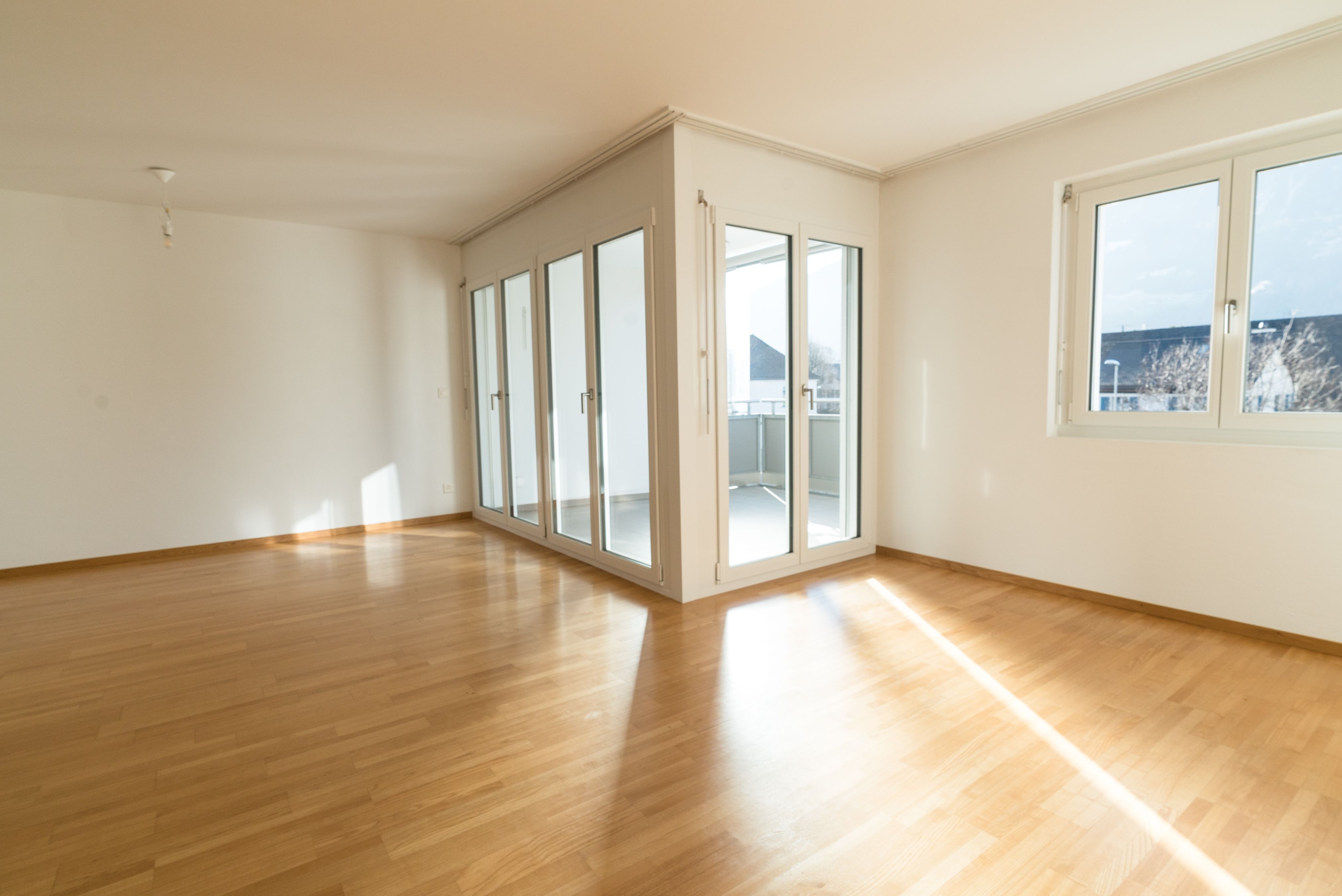 bright new living room in an empty apartment with french doors and parquet wooden floors