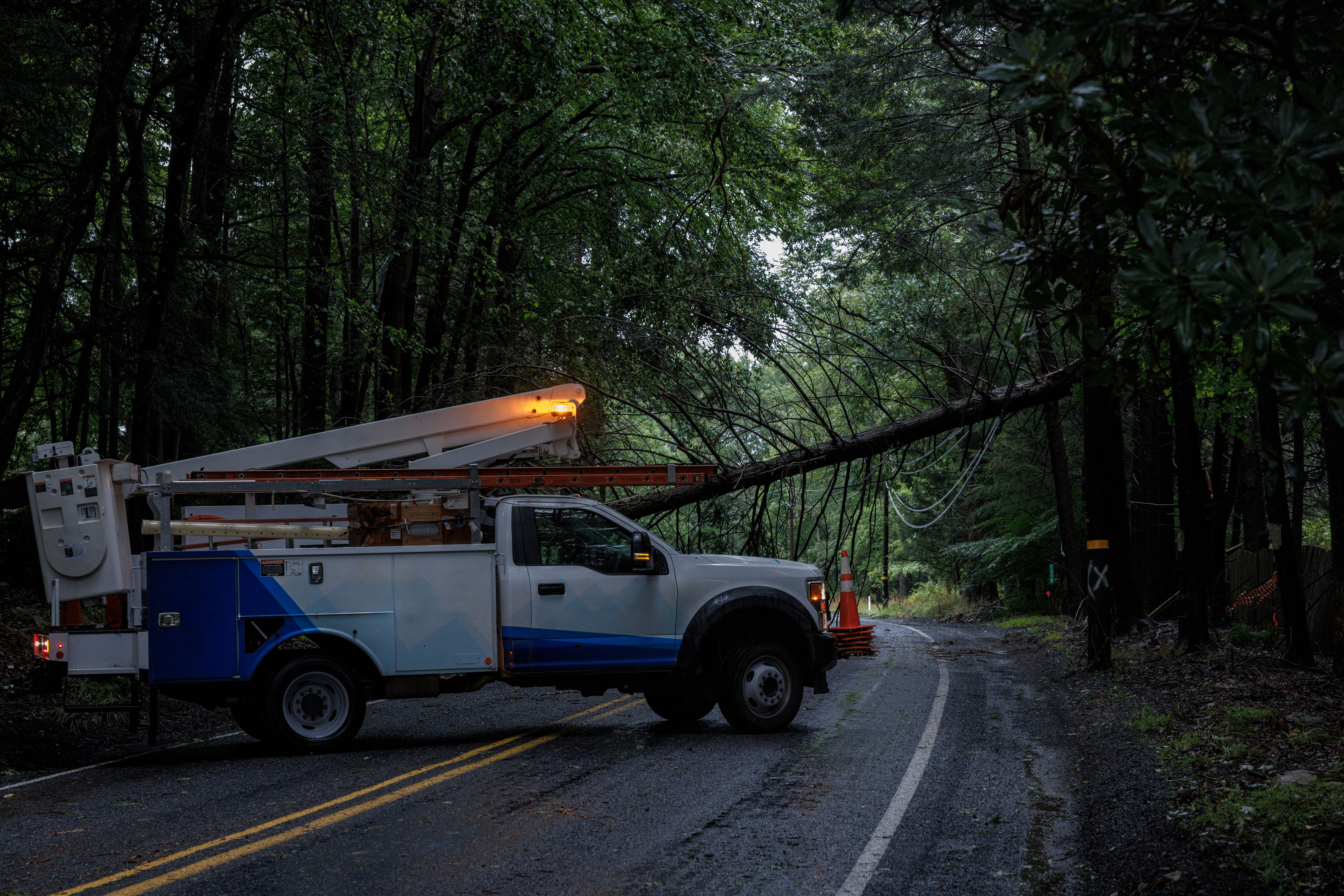Clearing storm aftermath in Poconos. Utility truck tackles fallen tree on winding forest road.