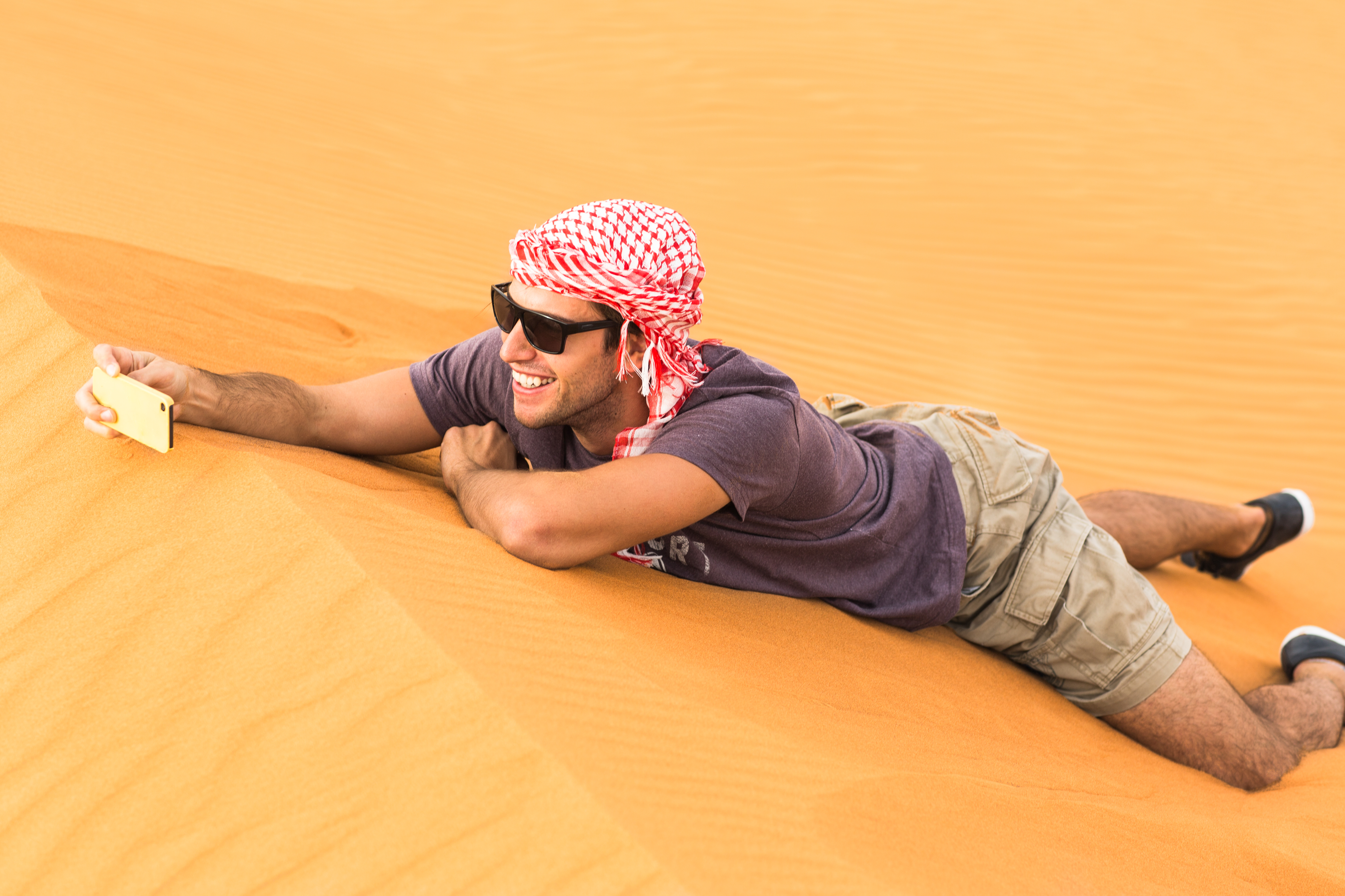 Male tourist taking a selfie picture with his phone in the desert.