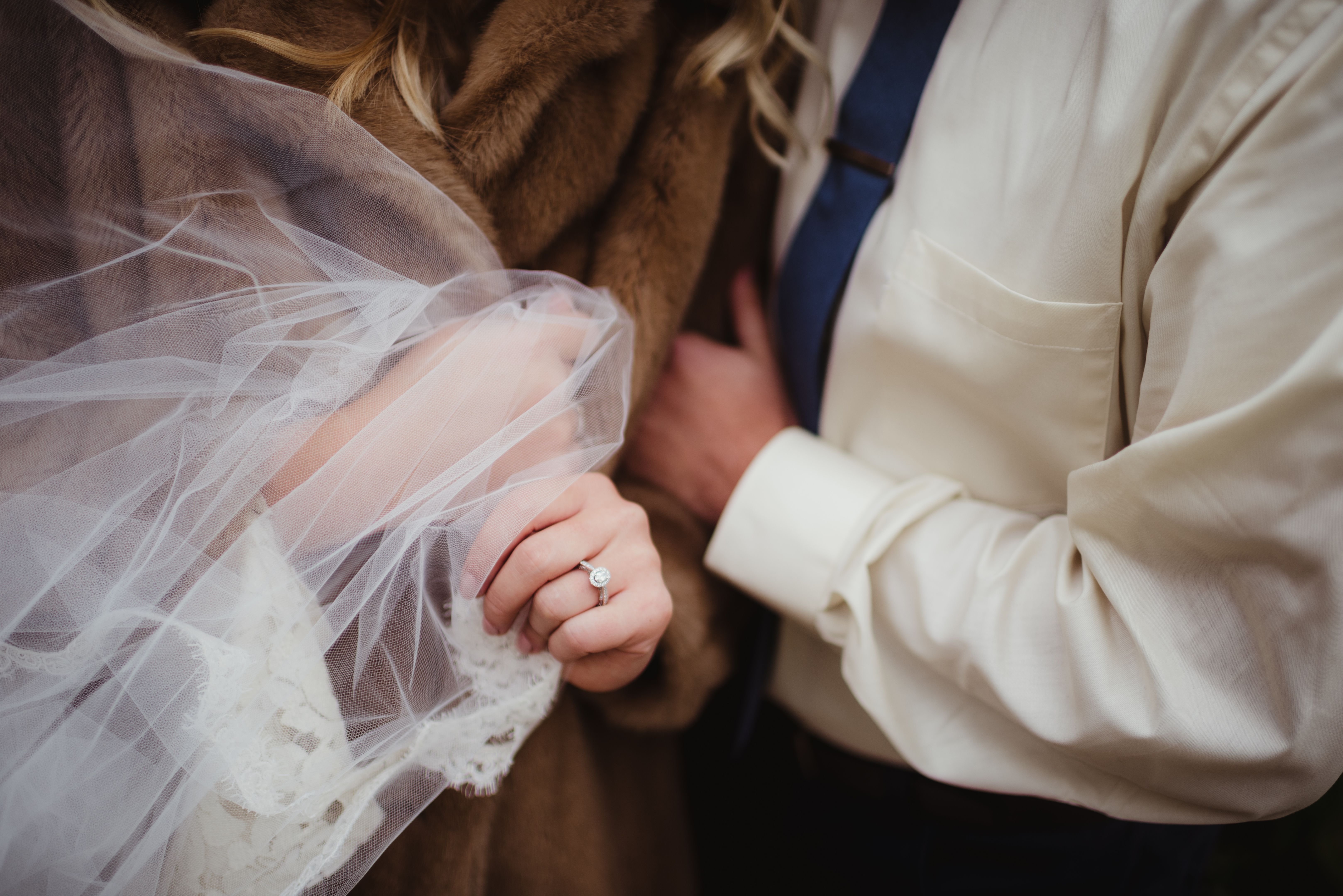 Bride and groom embracing with veil blowing in the wind Bride and groom embracing with veil blowing in the wind