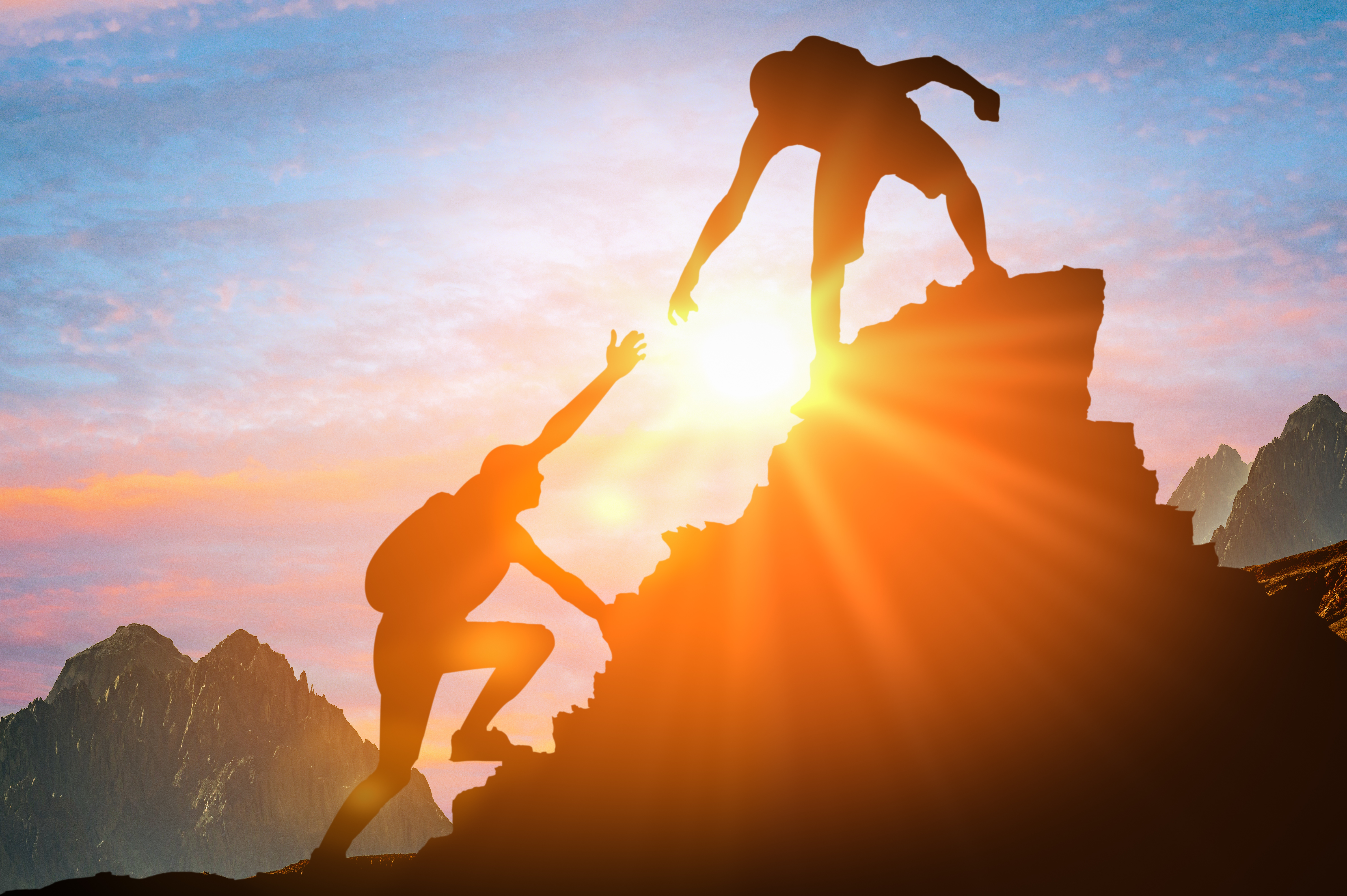 Man is giving helping hand. Silhouettes of people climbing on mountain at sunset. Help and assistance concept. Silhouettes of two people climbing on mountain and helping. Man is giving helping hand. Silhouettes of people climbing on mountain at sunset. Help and assistance concept. Silhouettes of two people climbing on mountain and helping.